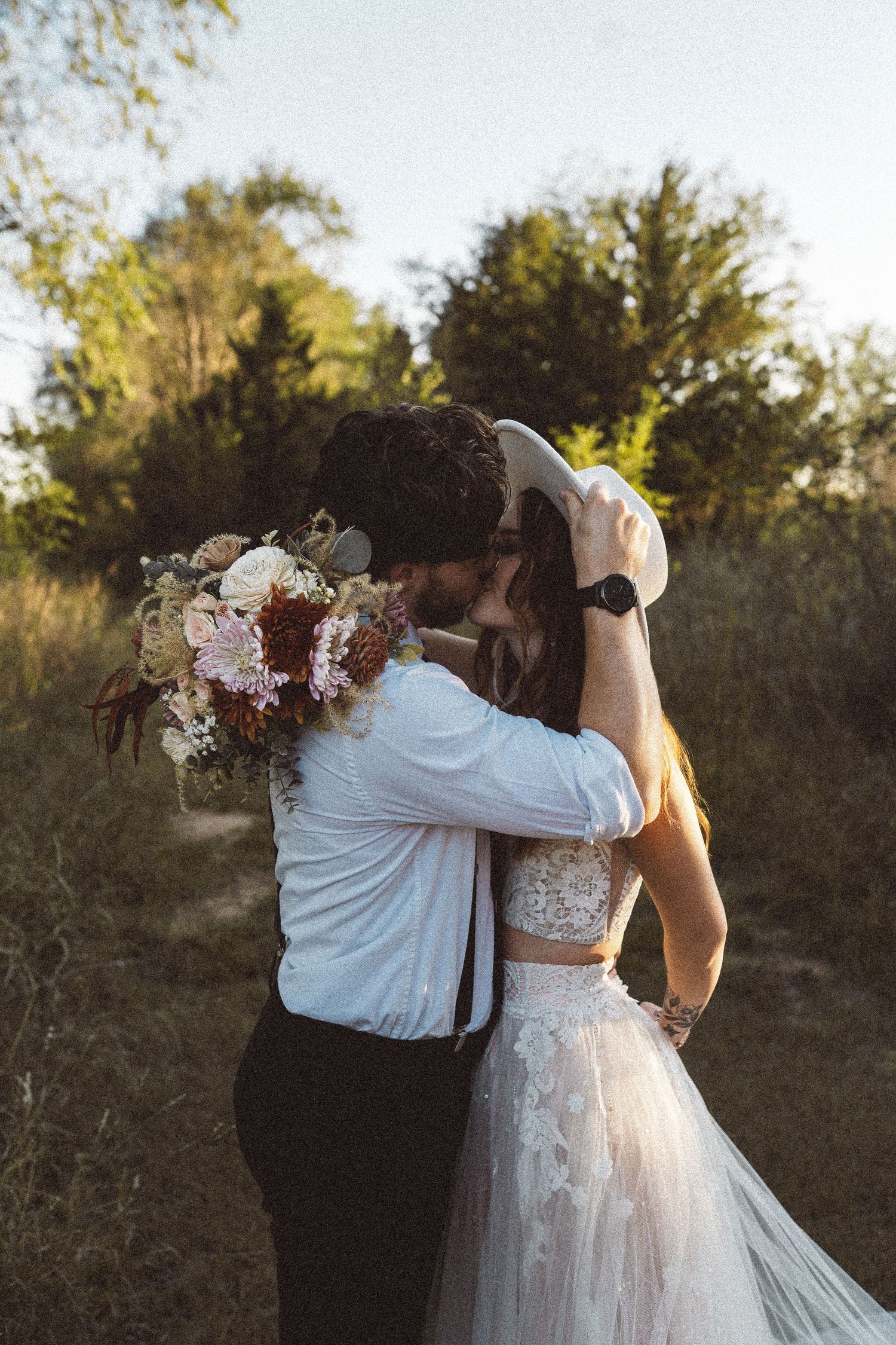 A tender embrace captured from behind against a natural outdoor backdrop.
