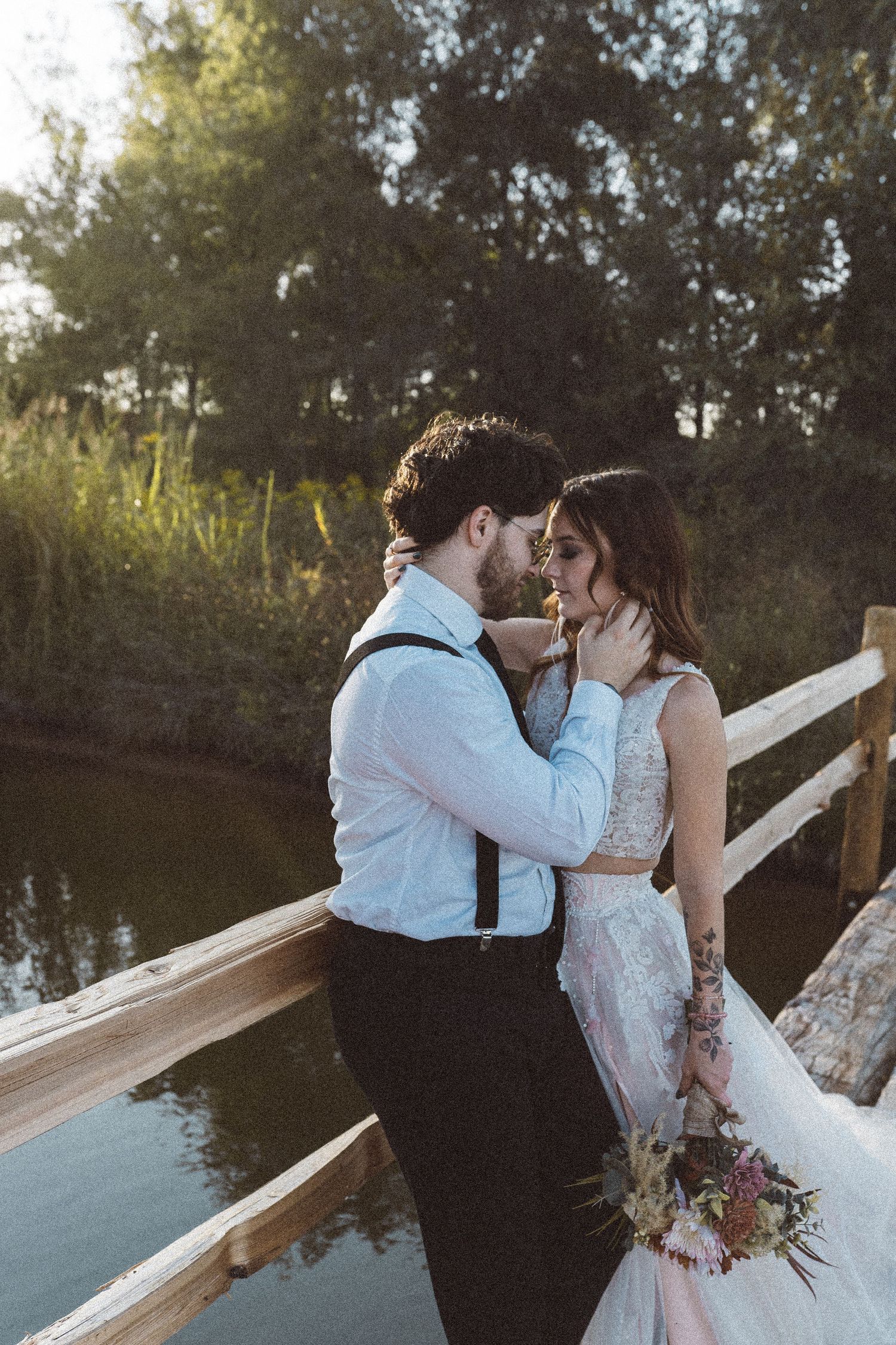 Intimate wedding portrait on wooden bridge with water reflection.