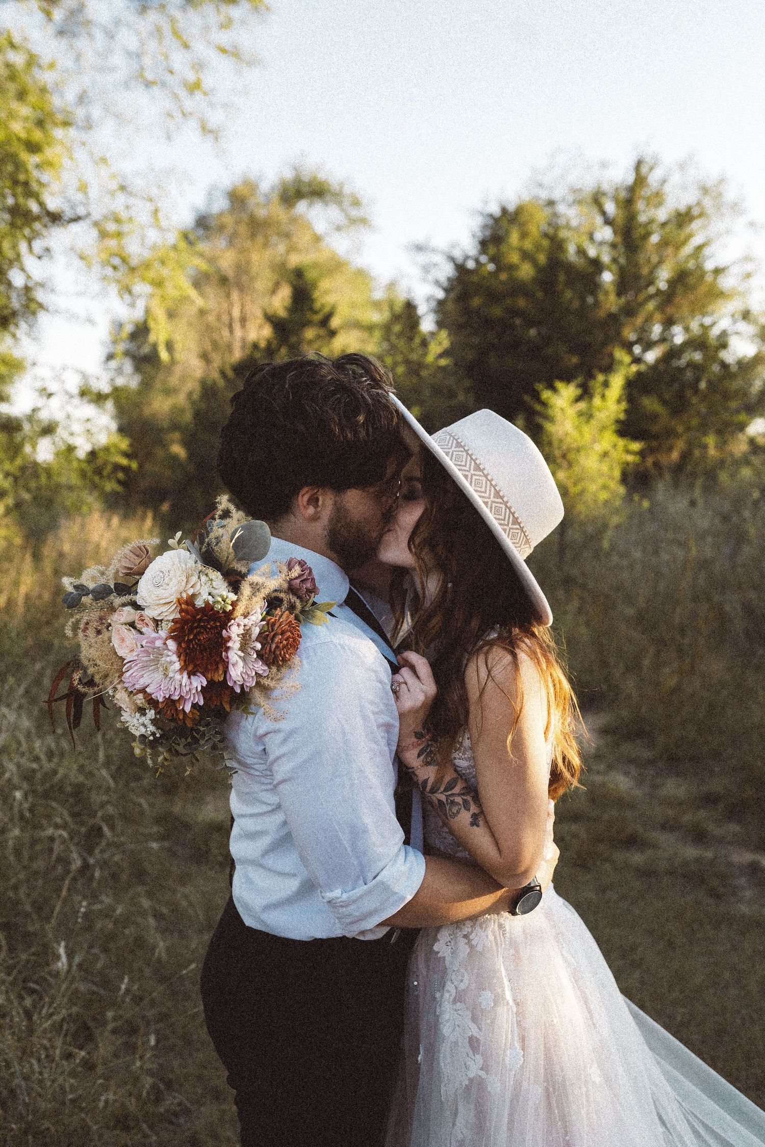 A tender wedding moment captured in warm evening light with floral details.