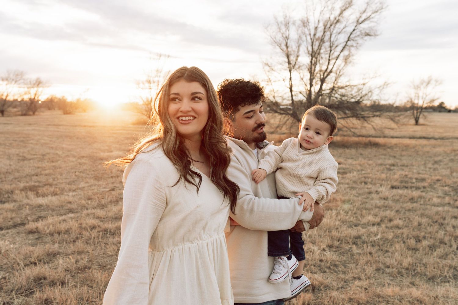 Happy family playing together in golden hour light across autumn field.
