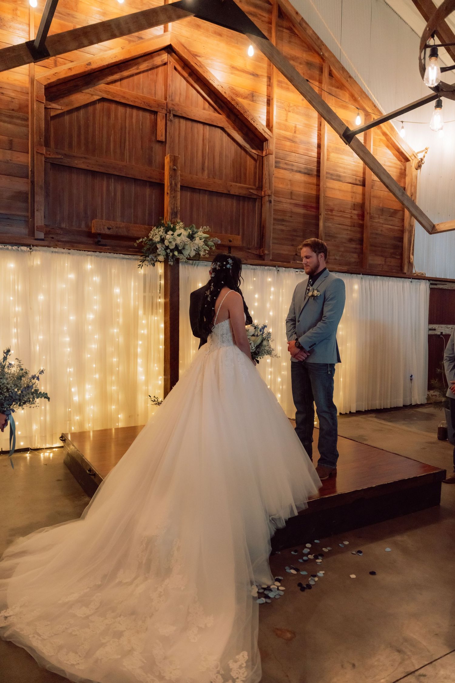 A rustic barn wedding venue decorated with string lights and white fabric draping.