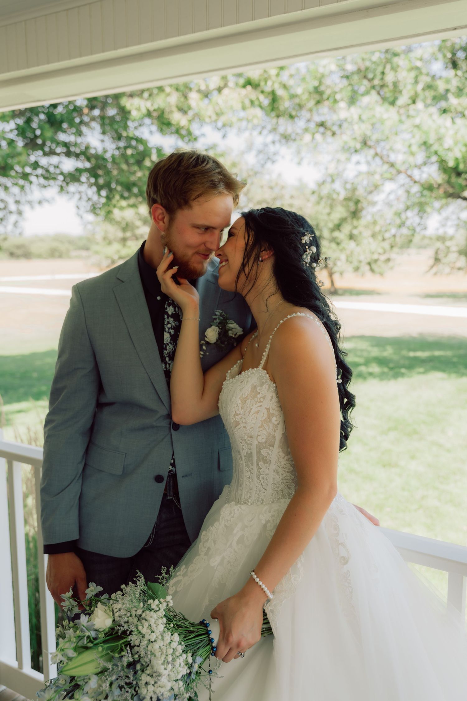 A romantic moment between newlyweds on a covered porch with soft natural lighting.