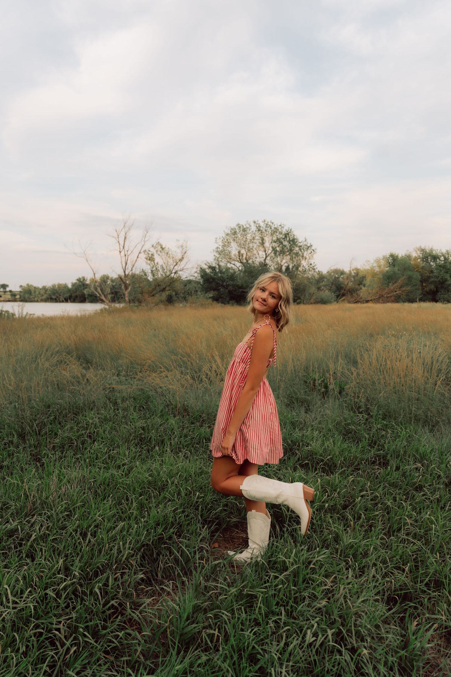 Person in pink outfit walks through a lush green field with trees on the horizon.