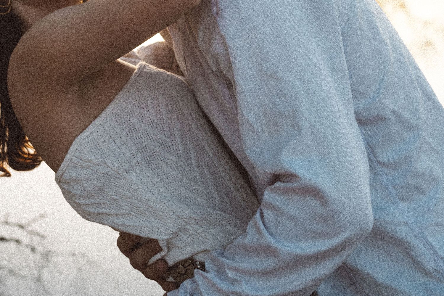 Close-up of people in white clothing embracing on the ground.