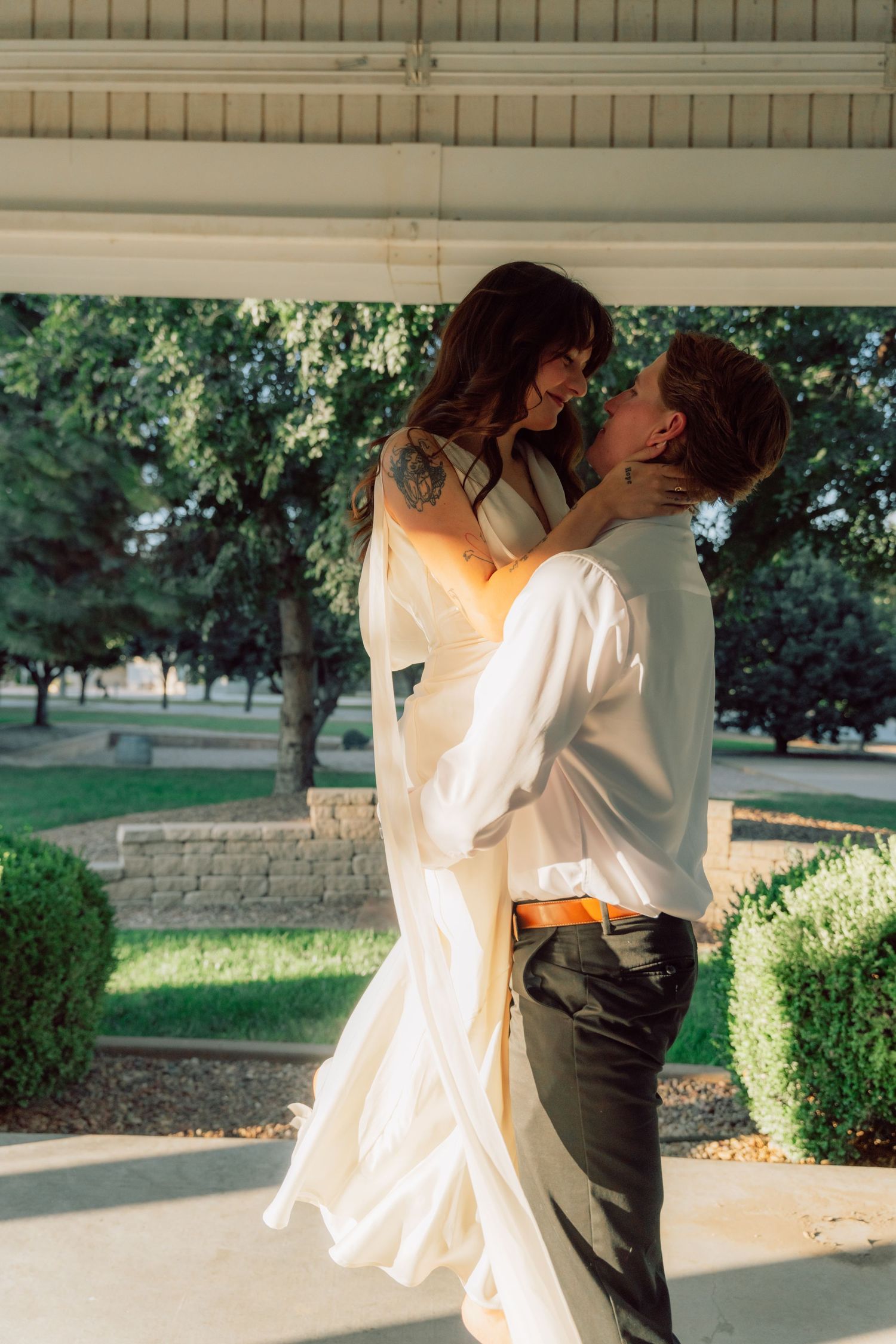 An intimate moment shared between a couple in formal attire under a gazebo.