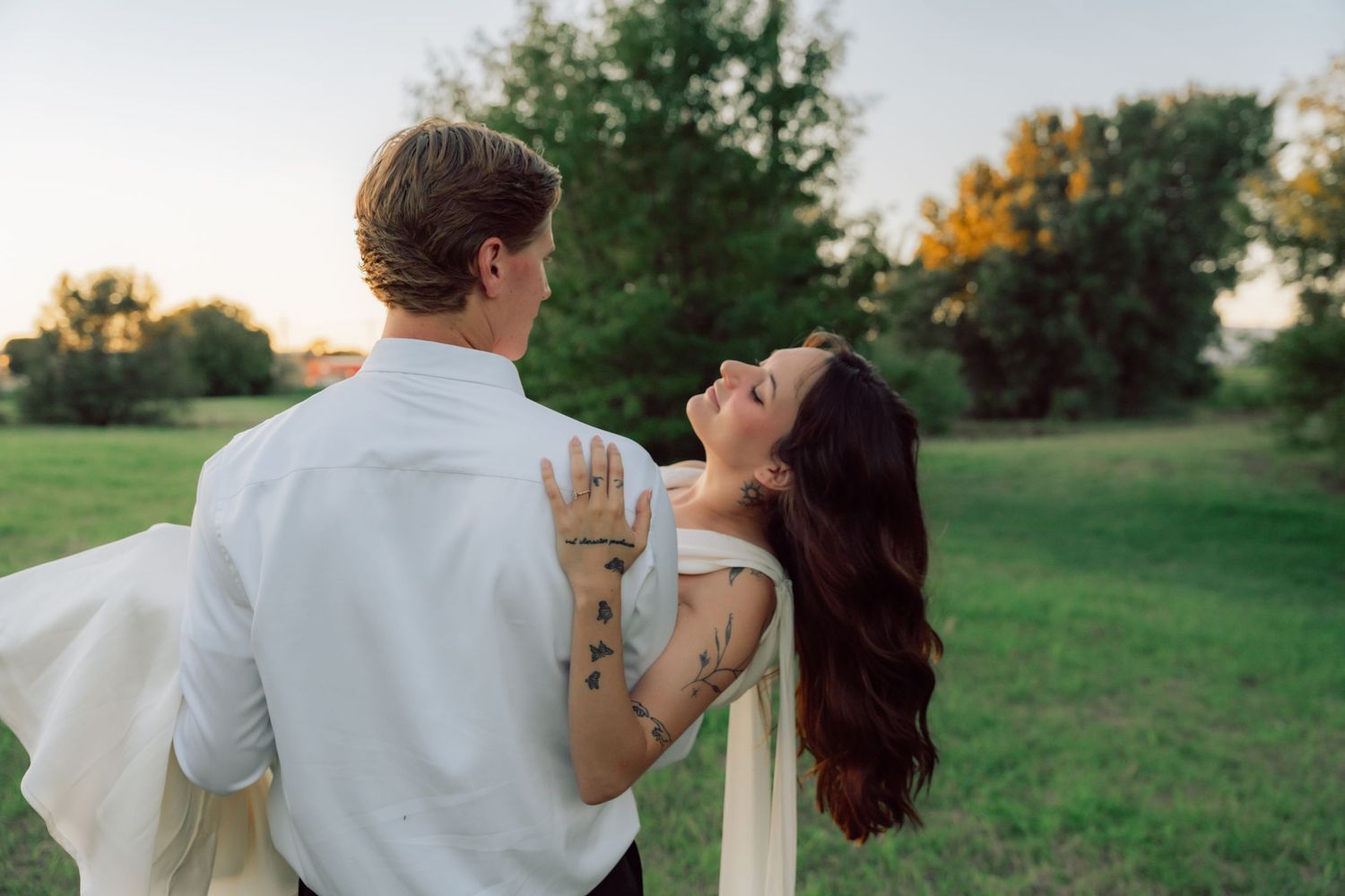 A romantic dip pose captured during sunset in a grassy field.