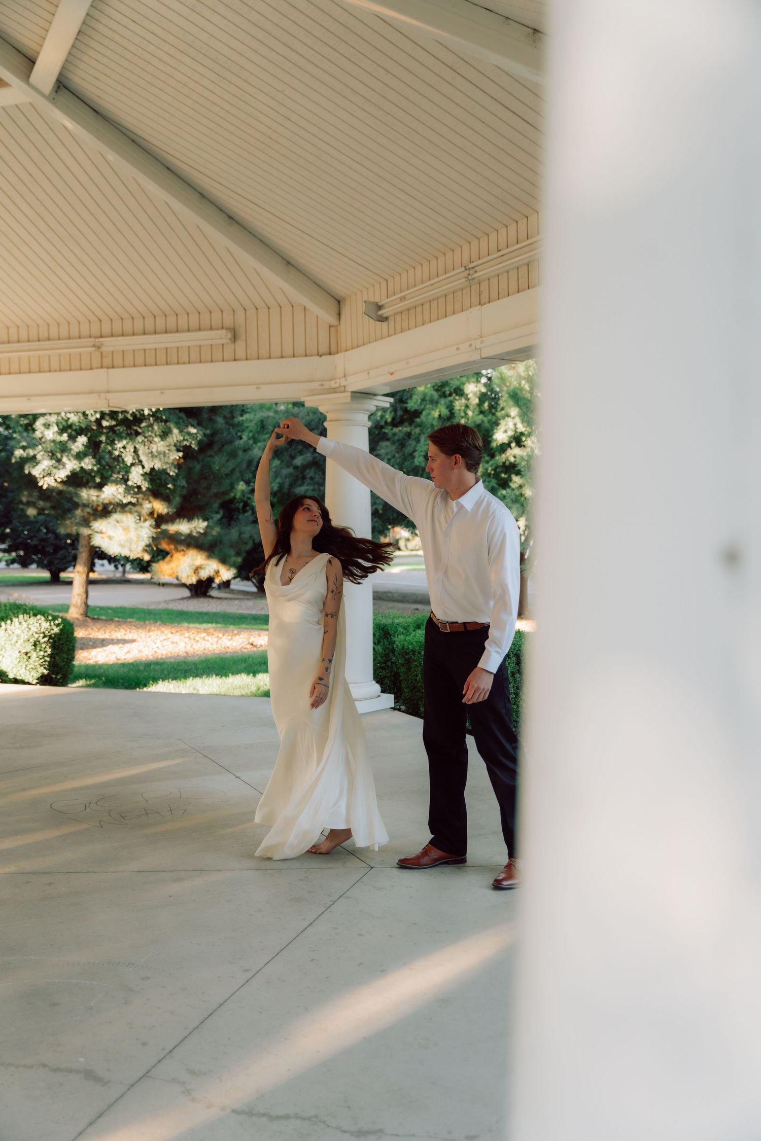 Couple dancing beneath covered porch during intimate wedding photoshoot.