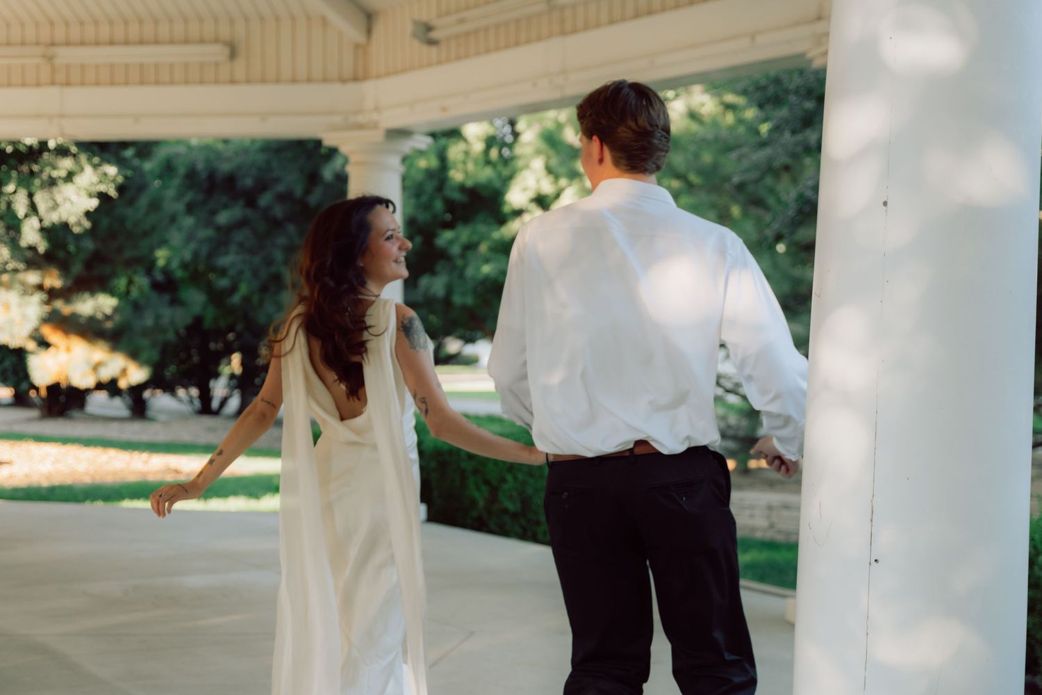 Couple dancing playfully on an elegant covered porch with white columns.