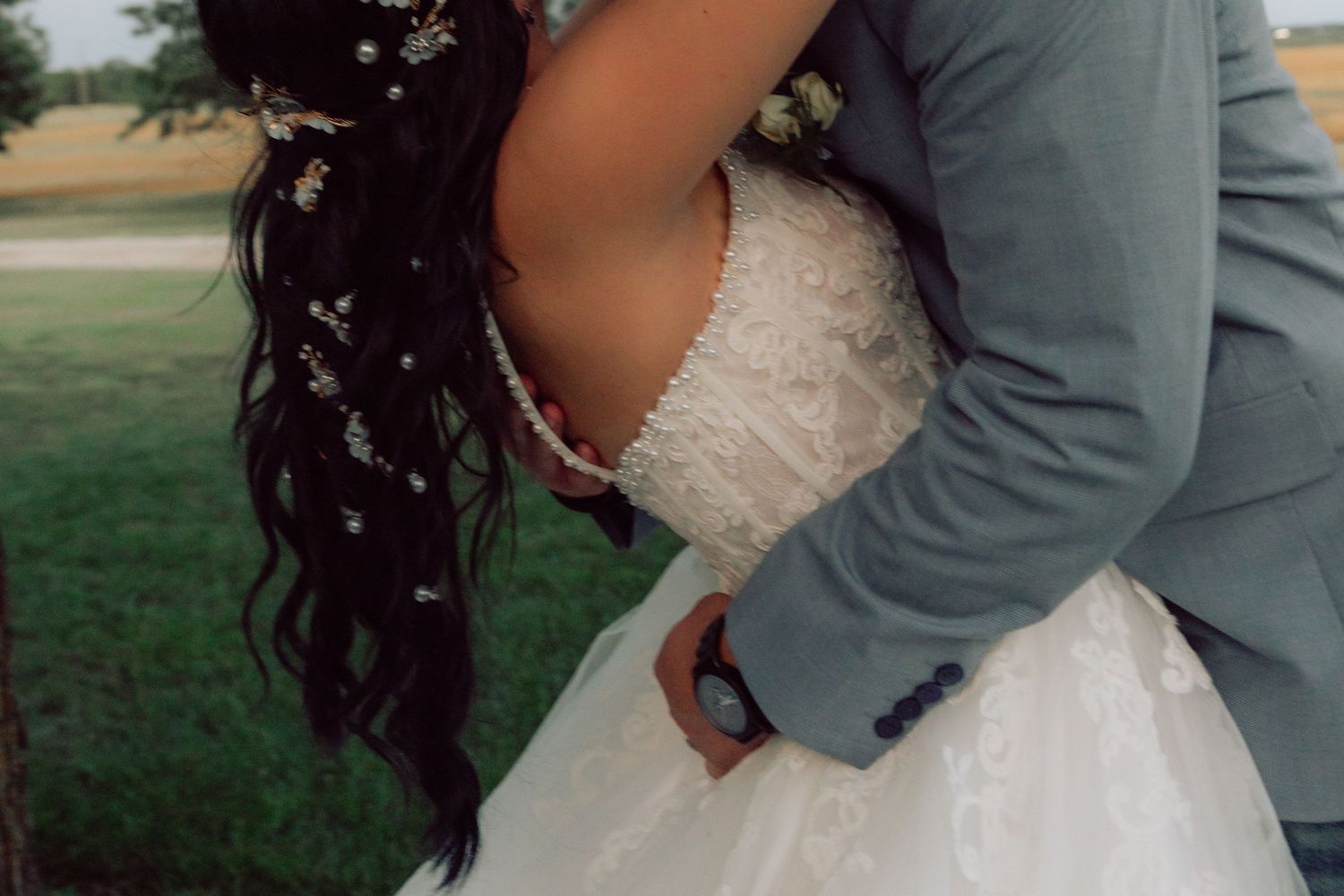 Wedding couple in an intimate embrace outdoors with the bride in a white lace dress.