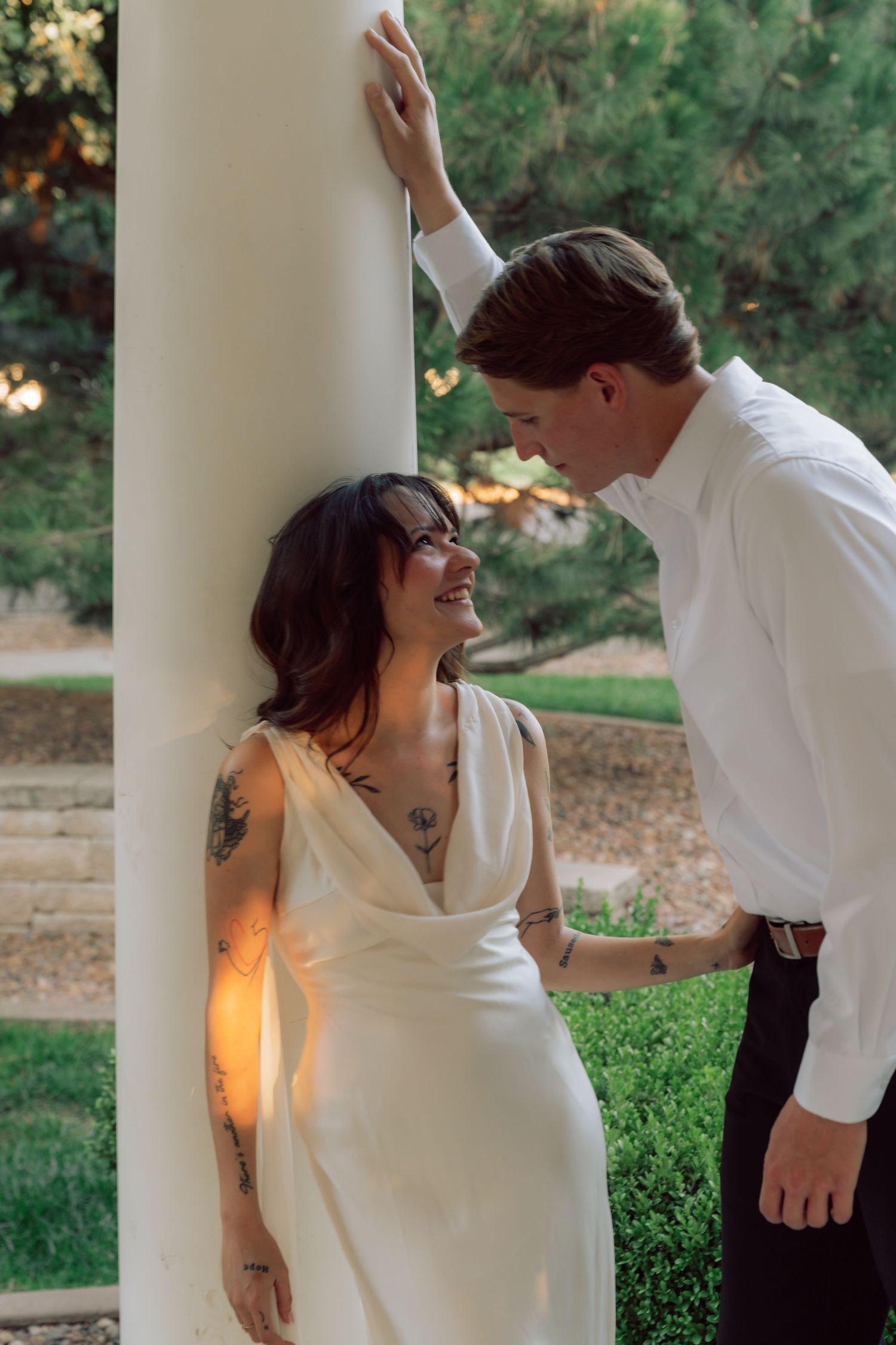 Joyful dancing moment between couple near white pillars in garden setting.