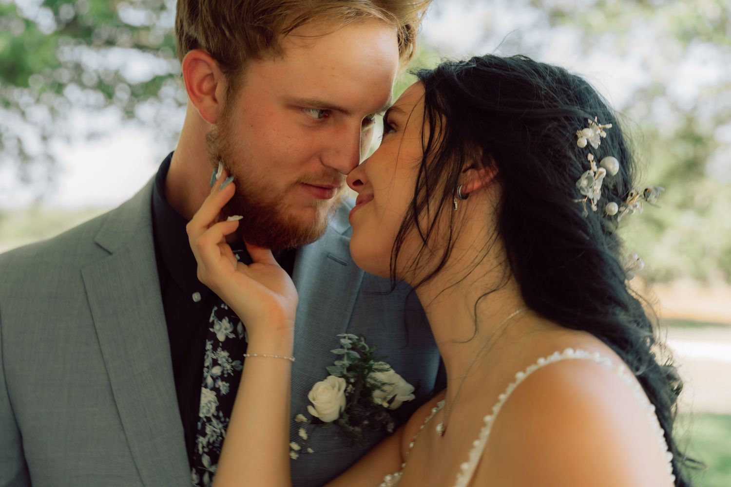 An intimate wedding portrait showing a tender moment between newlyweds outdoors.