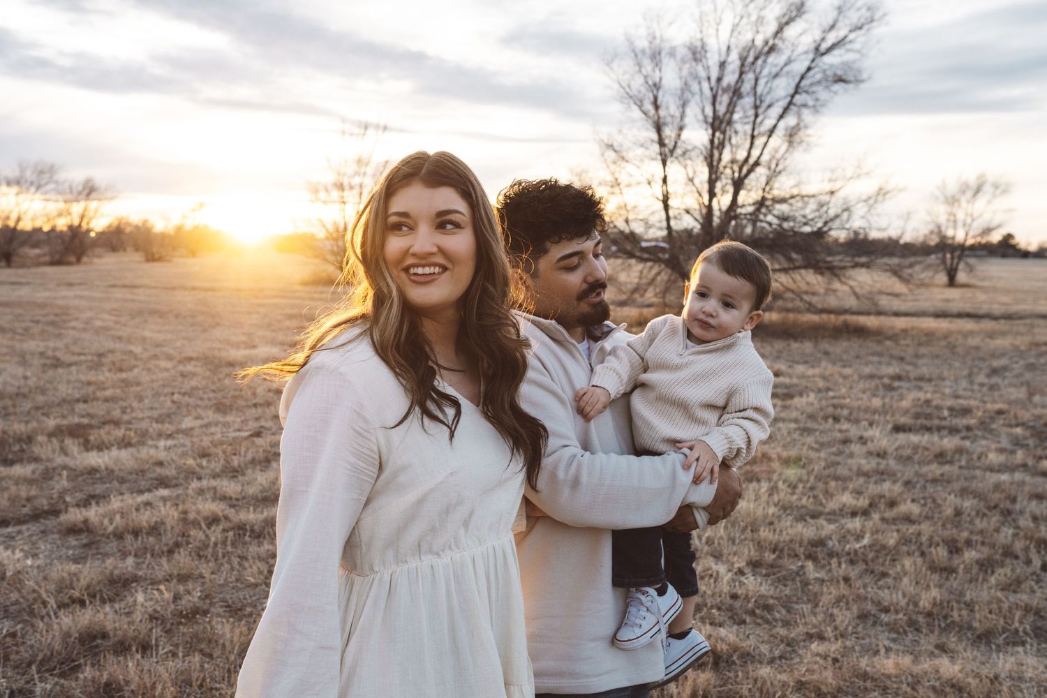 Family enjoying sunset moments in an open field with golden light.