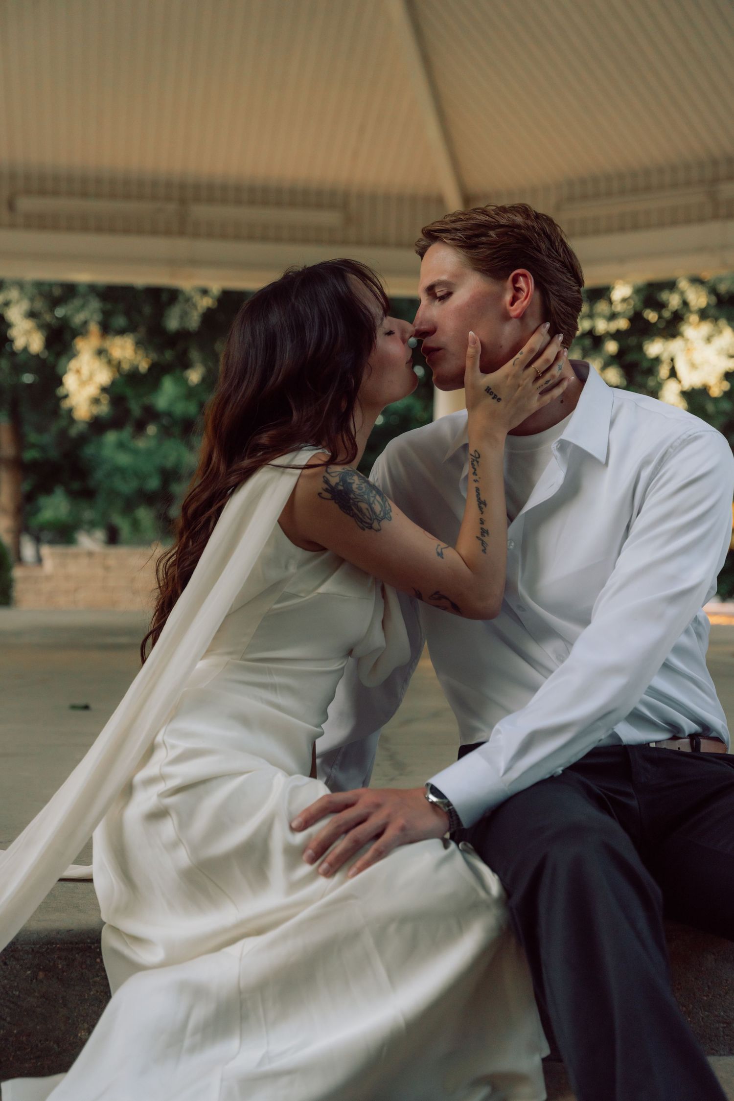 An intimate embrace captured in warm lighting under a gazebo.