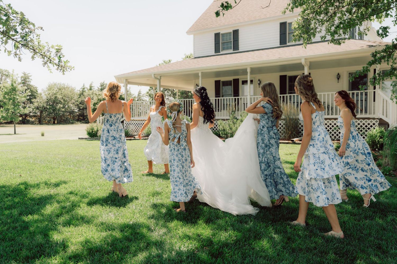 Candid moments of a bridal party in blue floral dresses celebrating on a sunny porch.