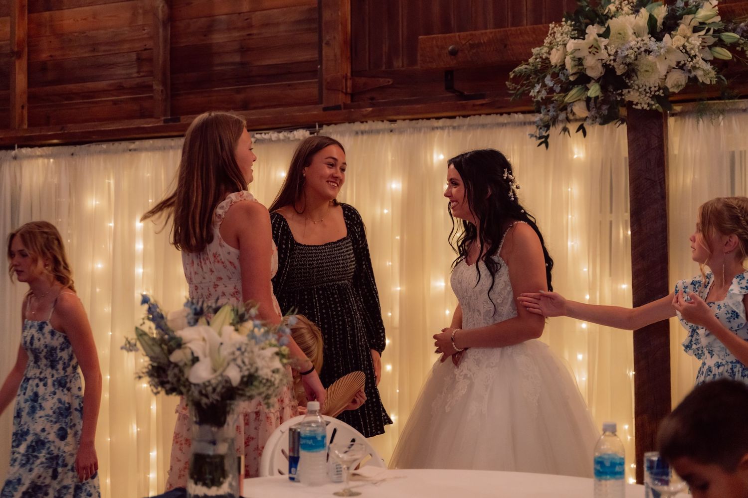 Wedding guests dancing and celebrating in a rustic barn venue with string lights.