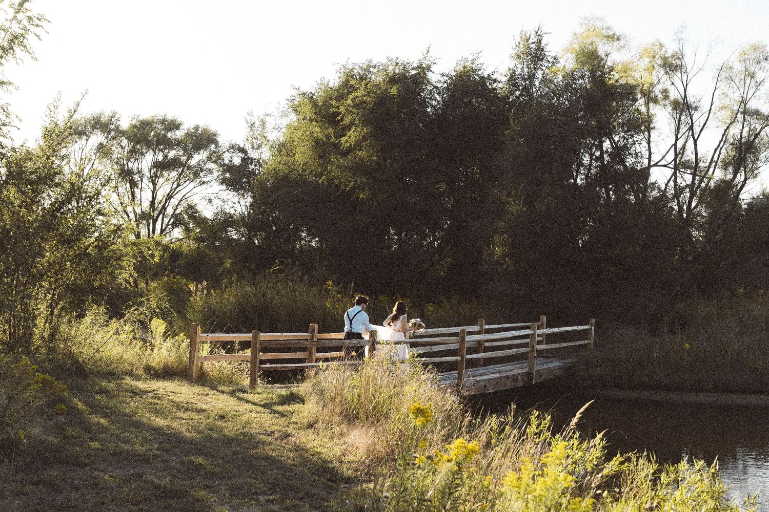 Natural landscape with wooden bridge and autumn foliage at sunset.