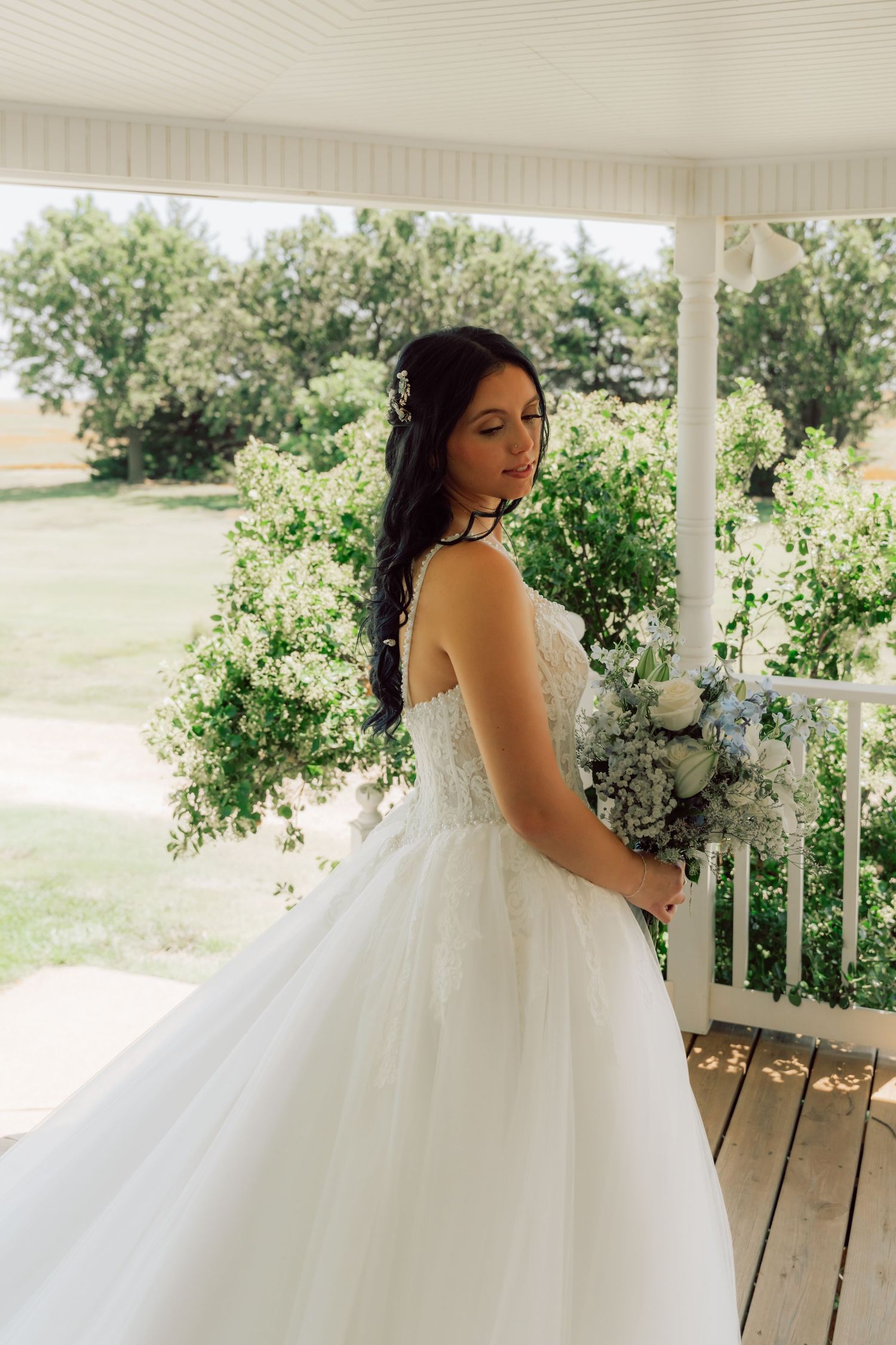 A flowing white wedding gown with lace details photographed on a wraparound porch.