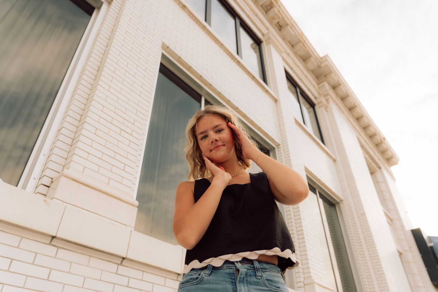 Urban fashion photography session featuring casual streetwear against white building exterior.