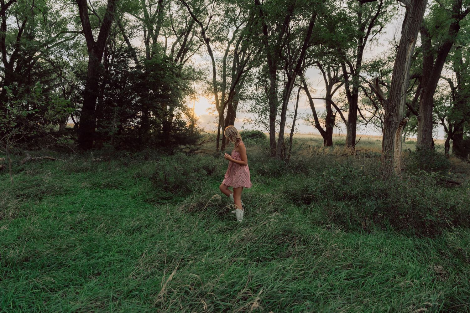 Figure walking through a wooded area during golden hour.