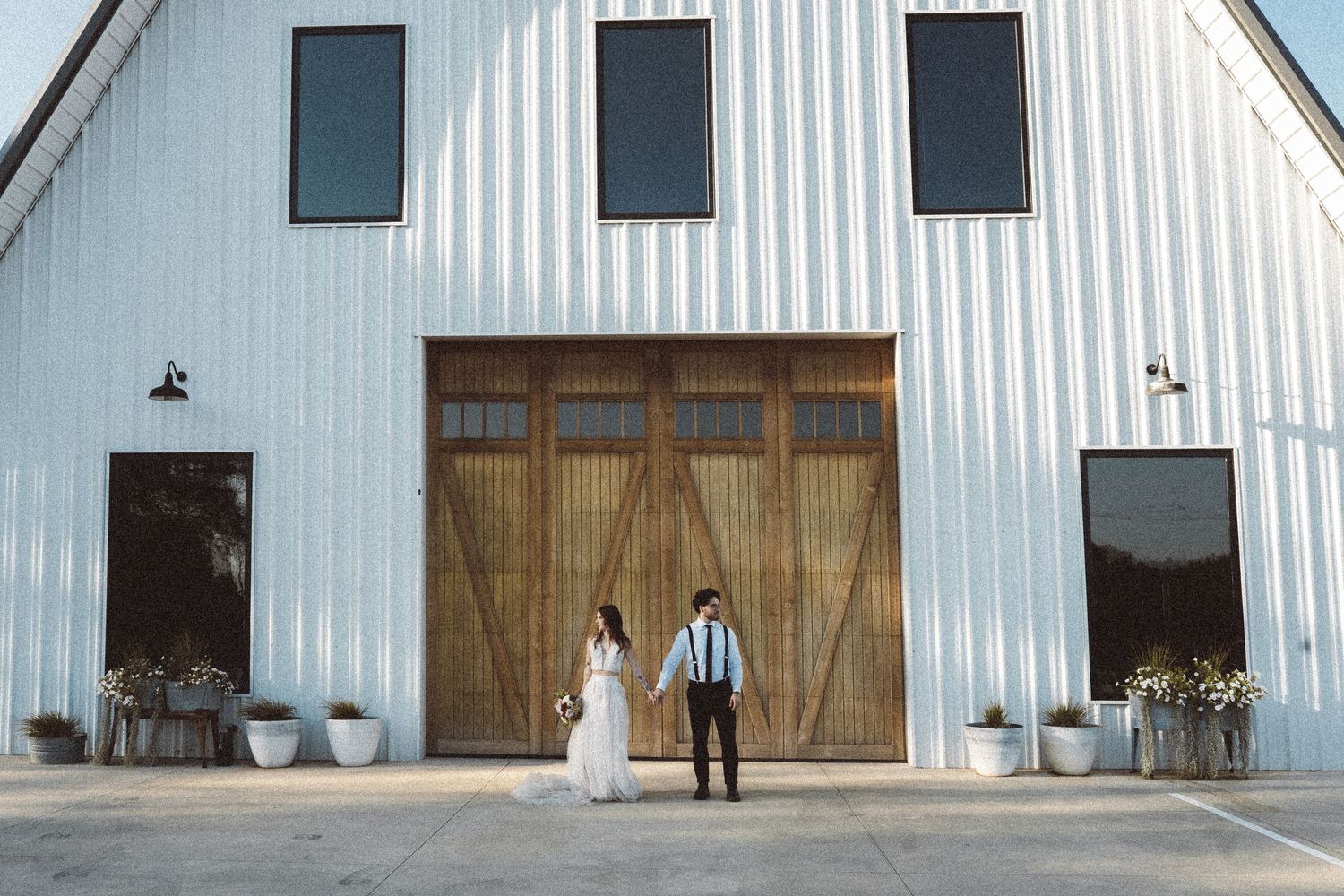 Modern white barn exterior with black windows and wooden doors.