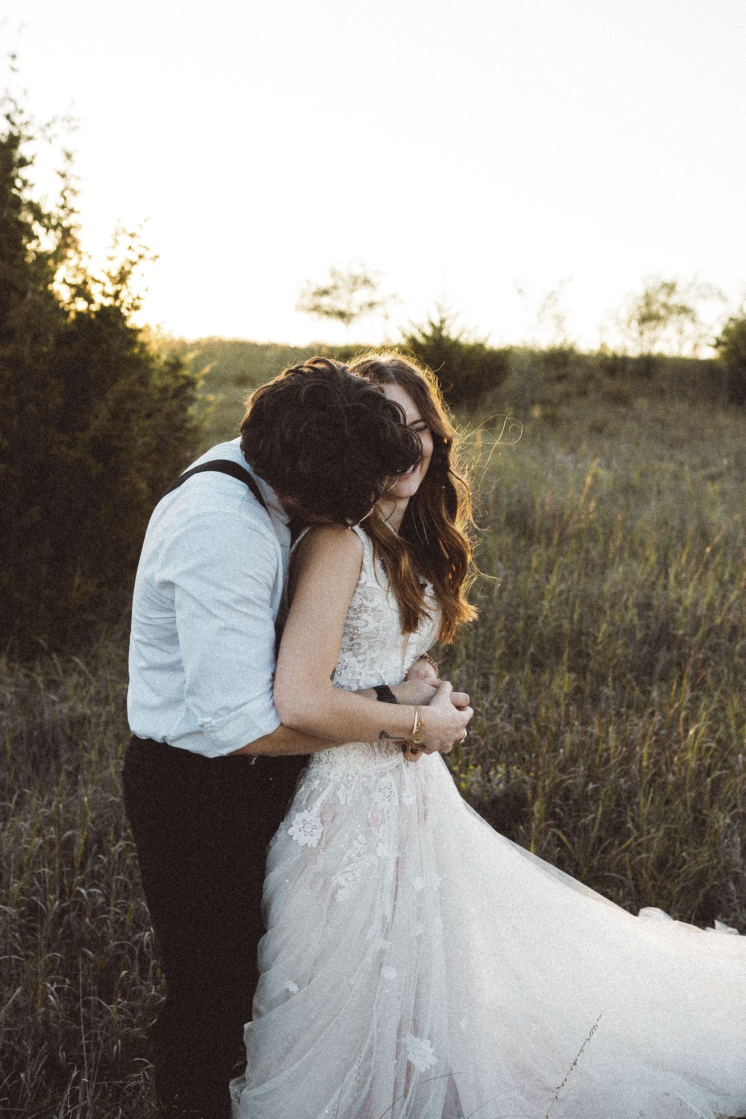 Sunset wedding photography with couple embracing in rustic outdoor setting.