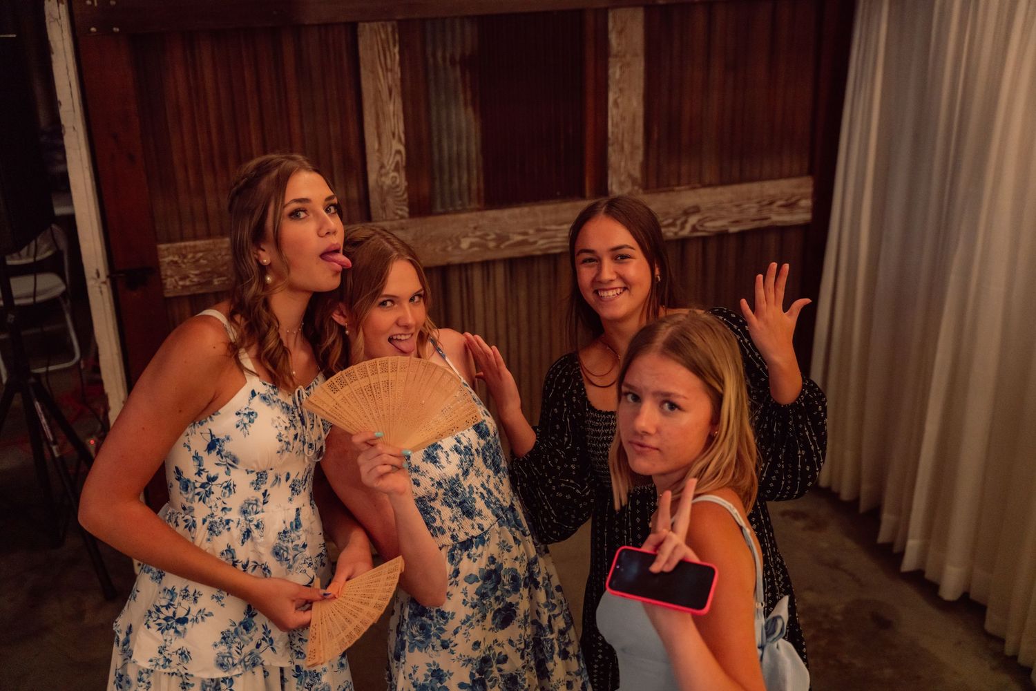 Wedding guests in floral dresses dancing and celebrating at a reception.