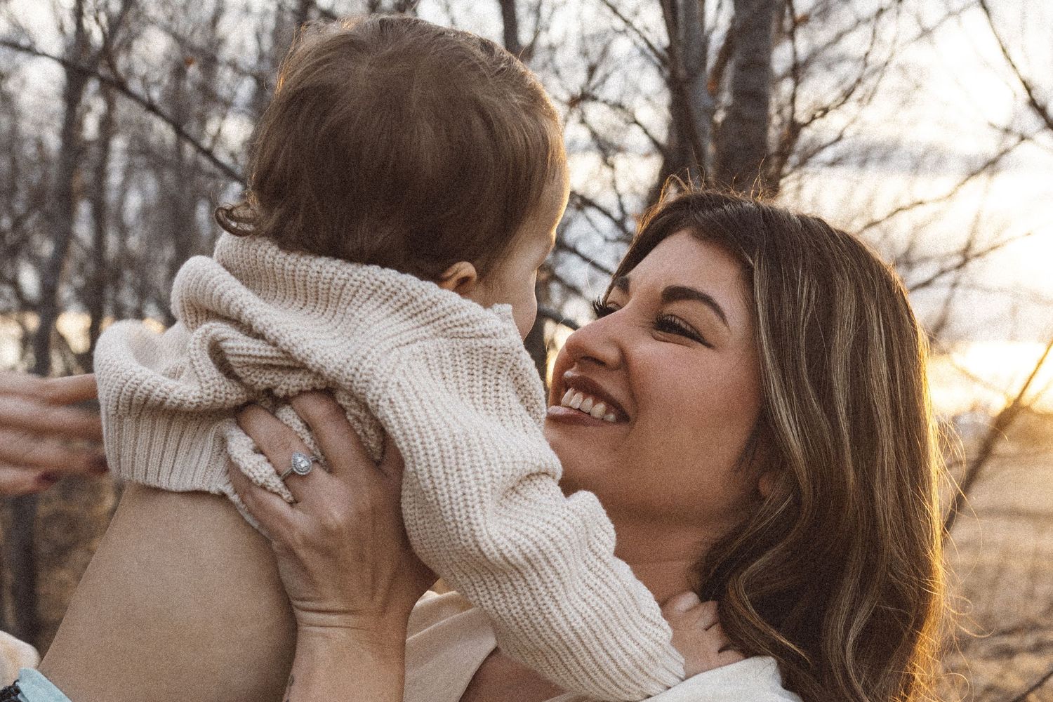 Joyful outdoor family photoshoot with warm sunset lighting in natural setting.