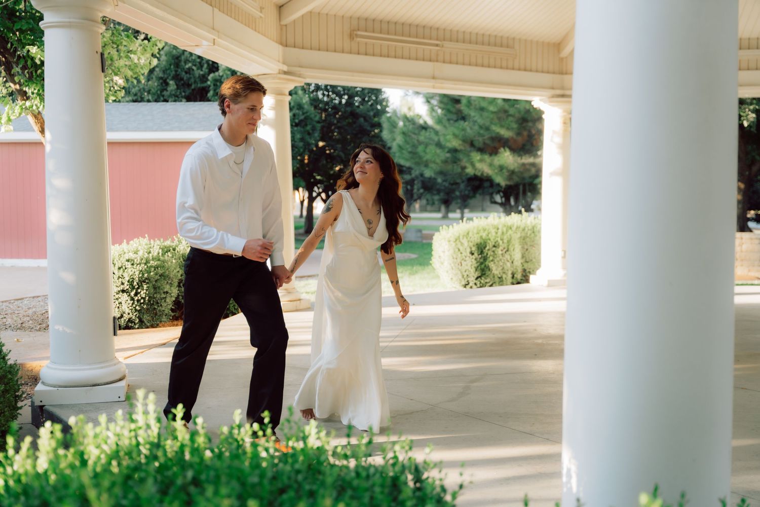 Couple laughing and dancing together on a white columned porch.