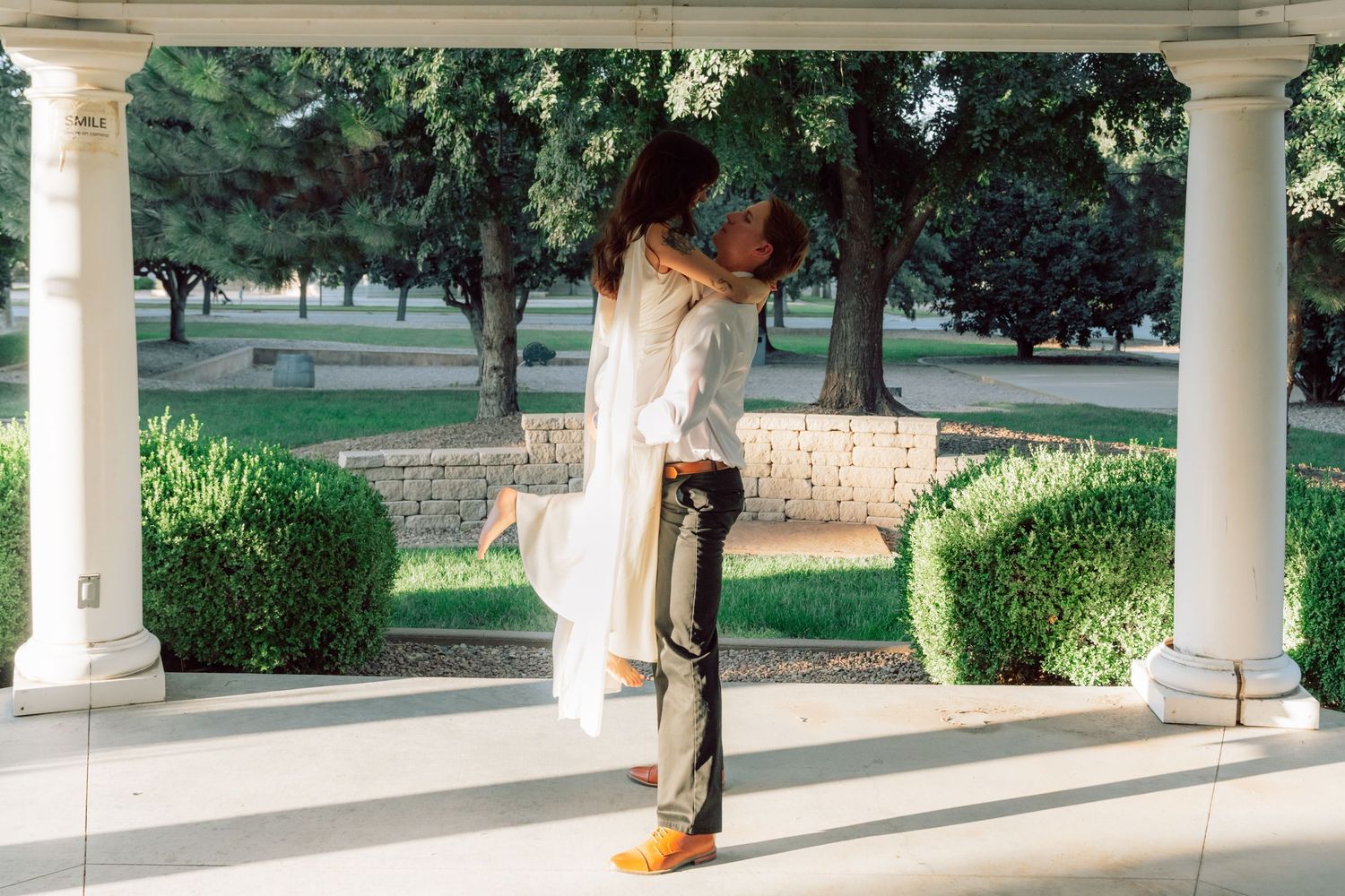 A romantic embrace in a white gazebo with garden views.