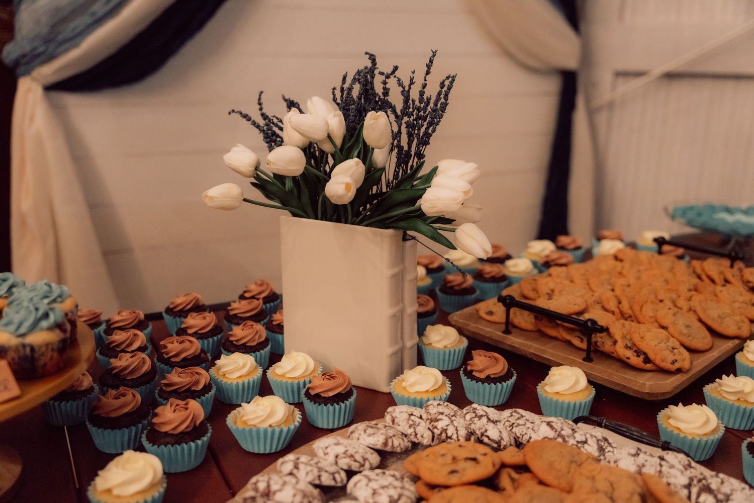 Wedding dessert display featuring cupcakes and treats arranged on a wooden table.