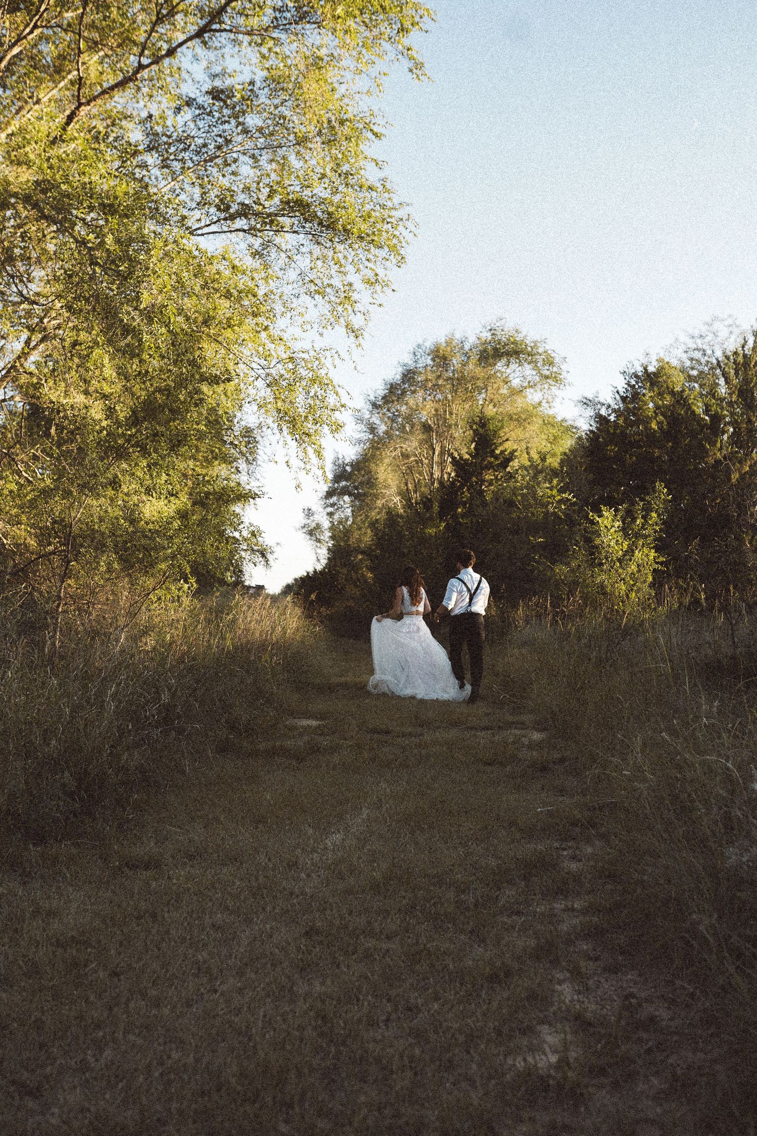 Two people stand together on a hillside path during golden hour.