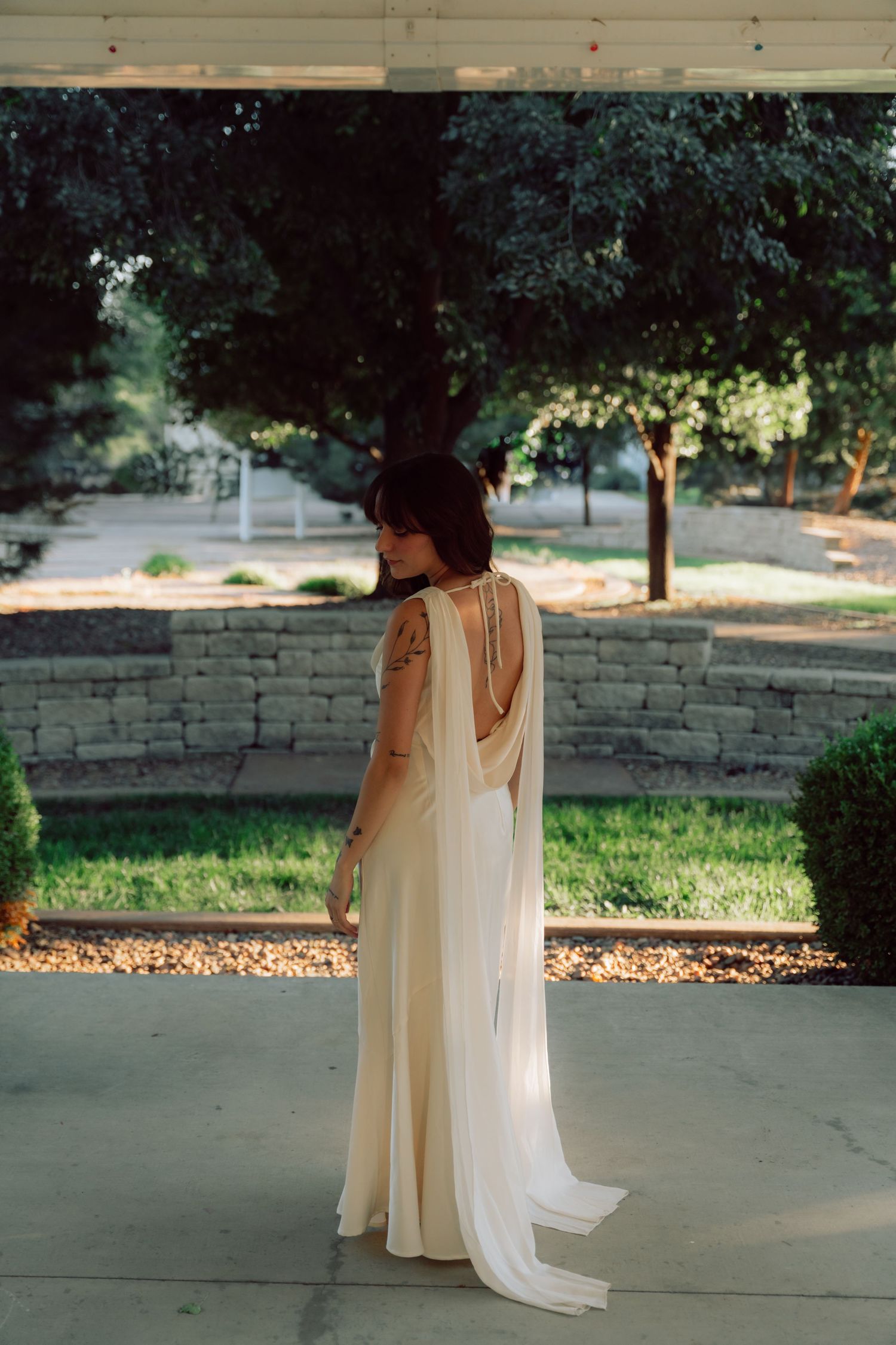 Elegant wedding dress with flowing cape detail photographed from behind.
