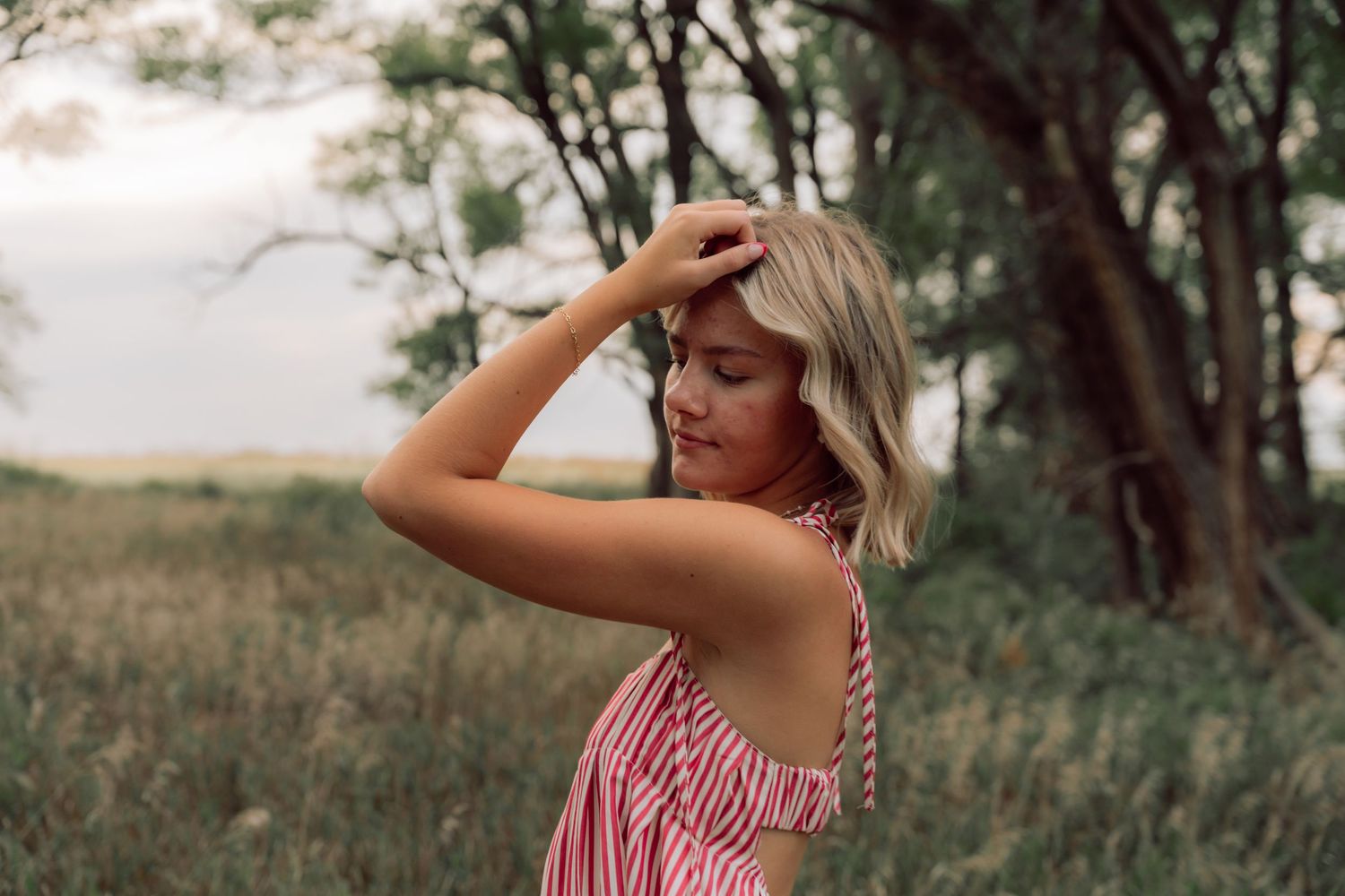 Artistic outdoor portrait in natural setting with trees and grass.