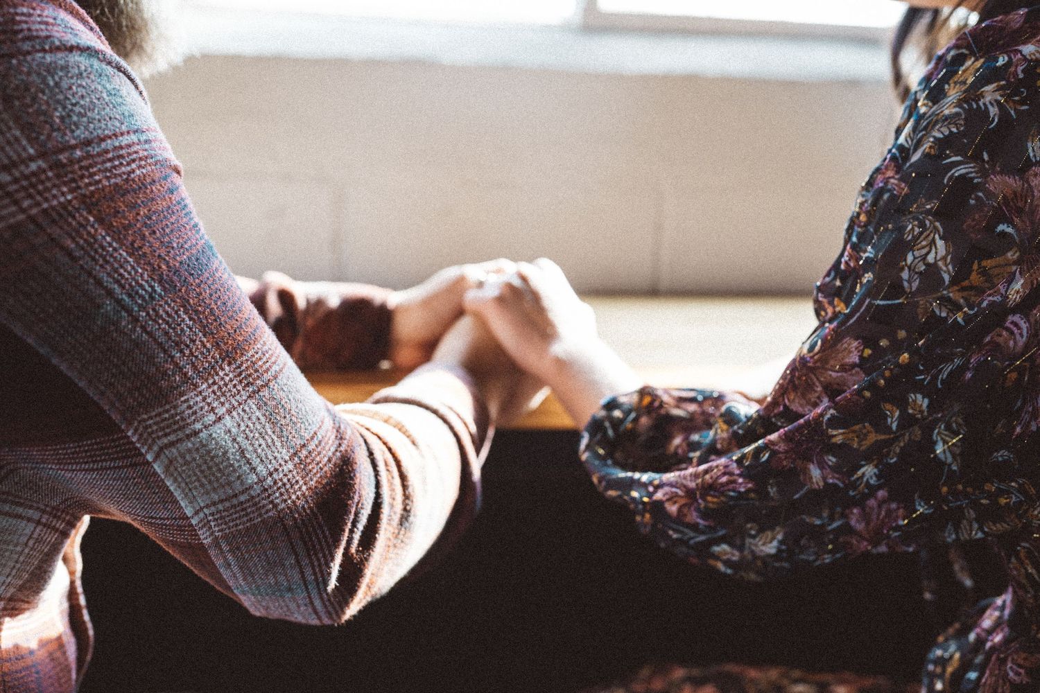 Close-up of hands resting on plaid fabric in soft lighting.