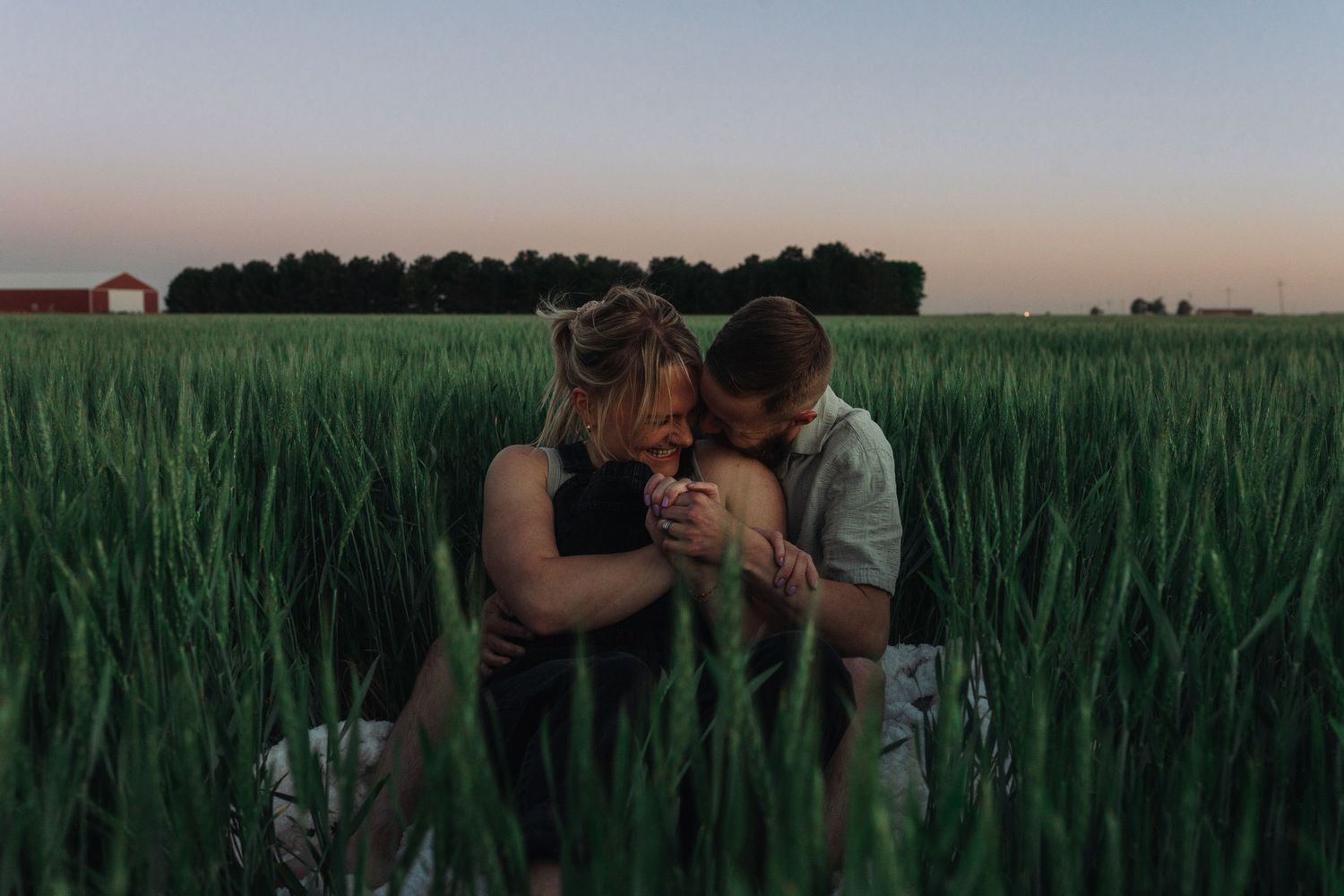 Romantic sunset photoshoot in a tall grass field with warm golden lighting.