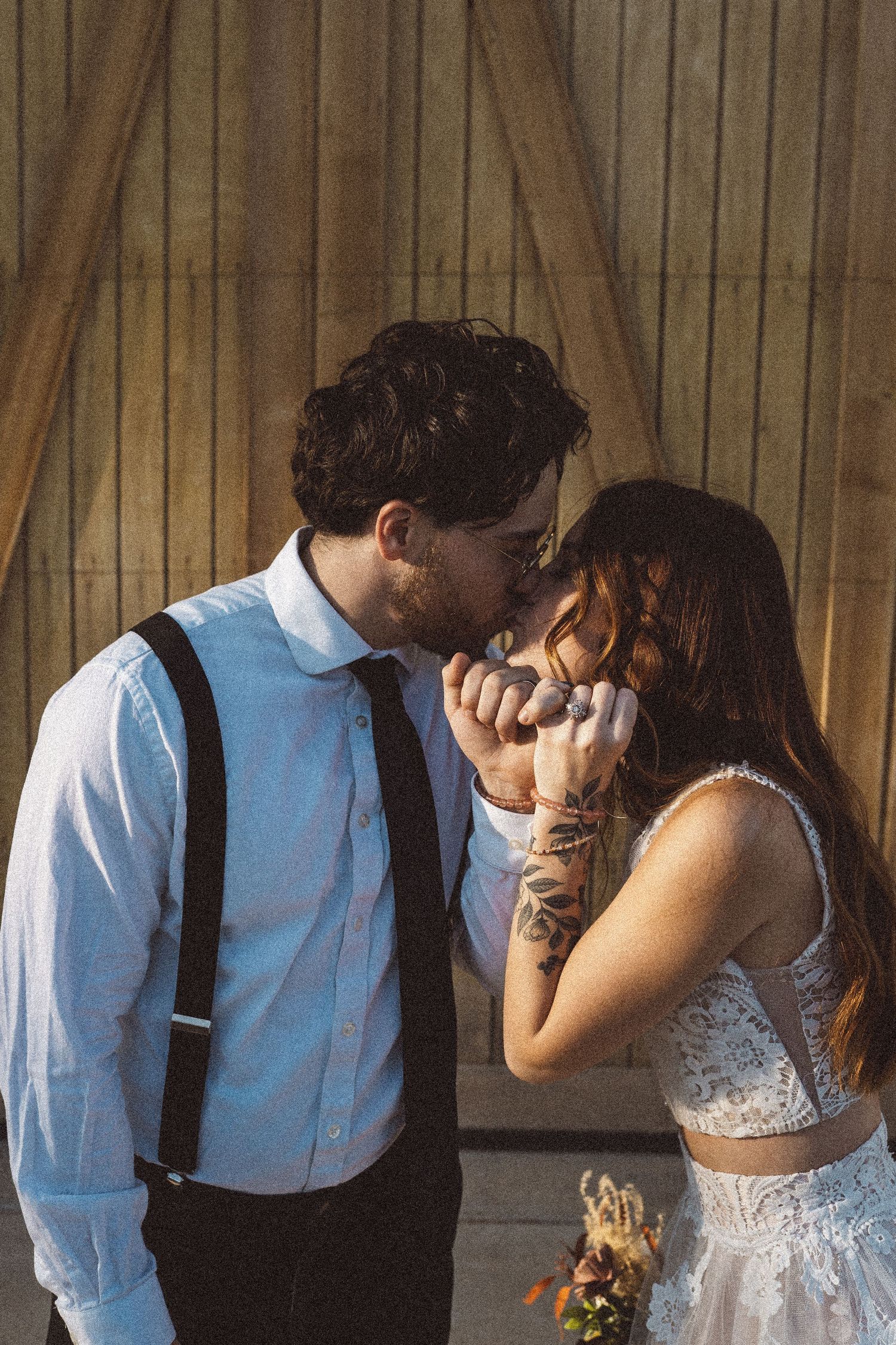 Intimate moment captured between newlyweds against rustic barn backdrop.
