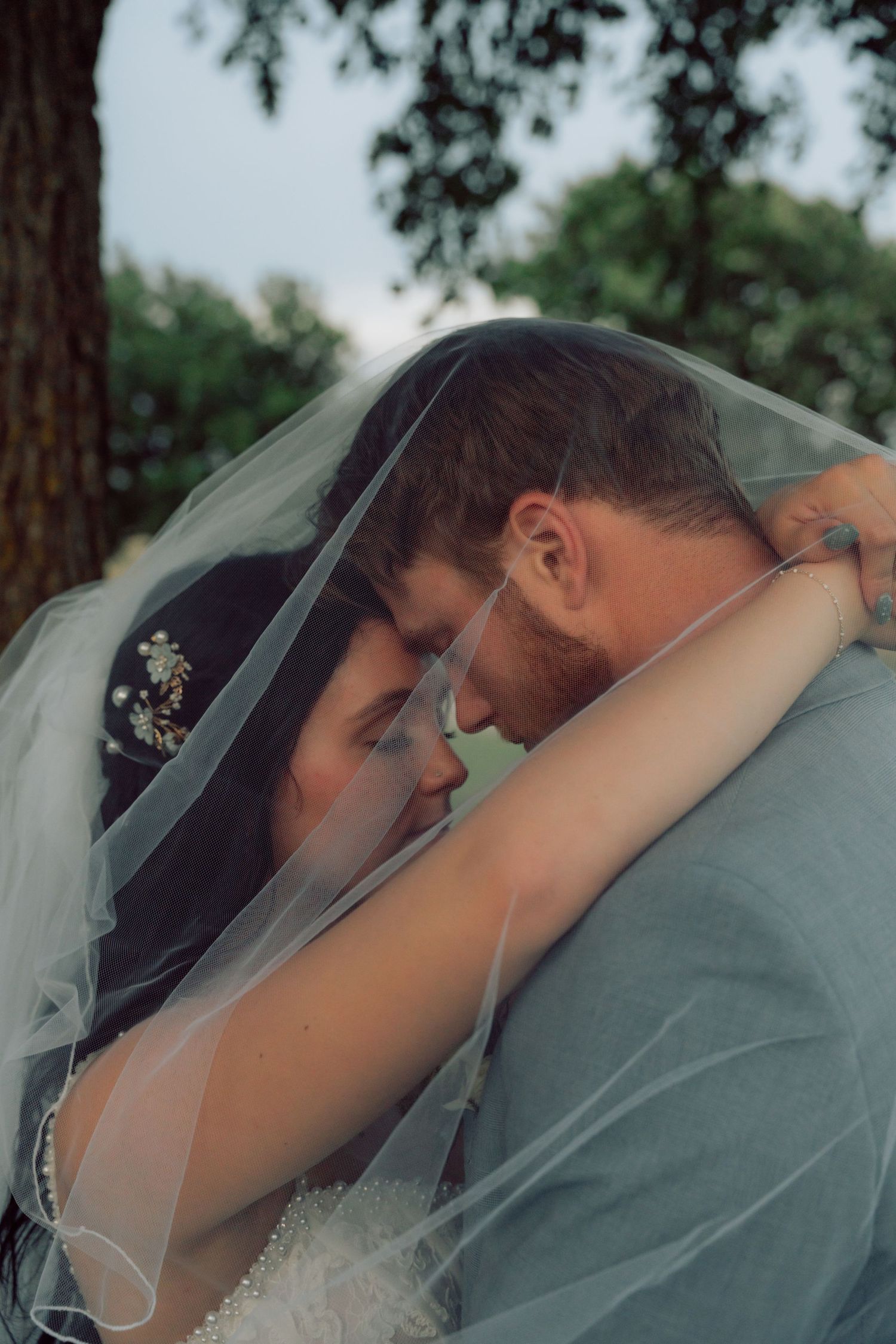 An intimate moment between newlyweds under a delicate white veil.