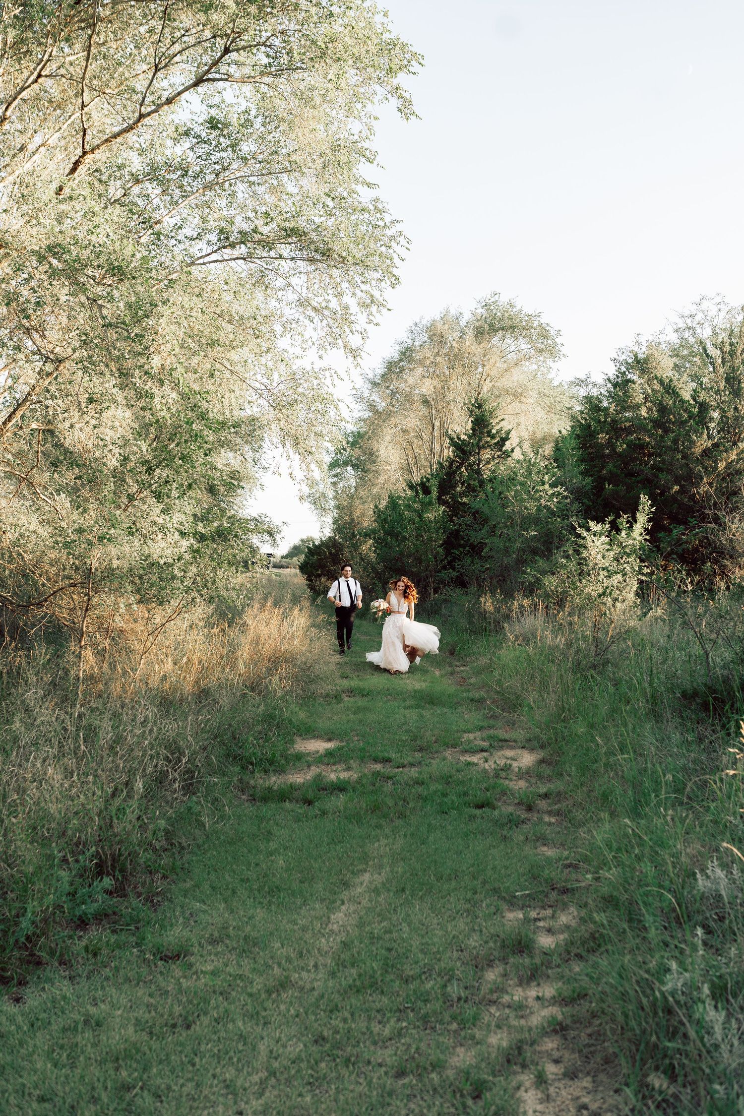 A grassy path leads through trees and bushes in a natural outdoor setting.