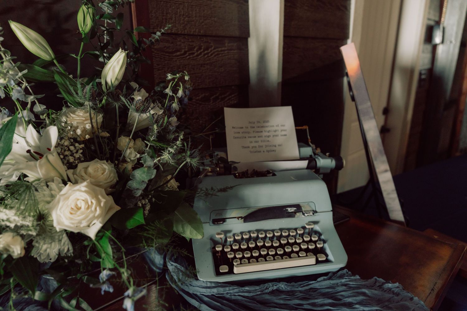 Wedding reception dessert table with vintage typewriter and floral decorations.