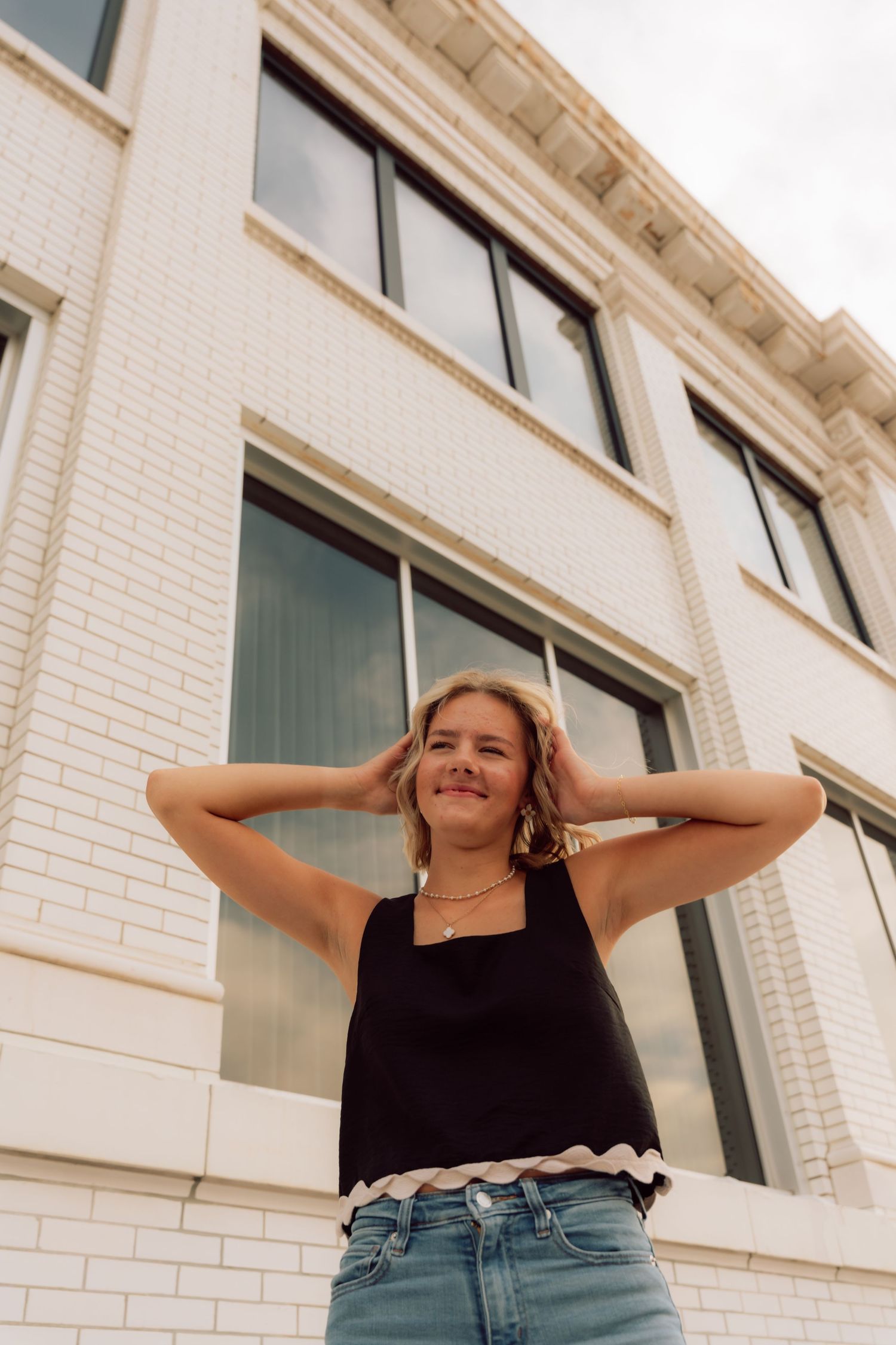 Playful poses captured against white brick architecture in summer casual wear.