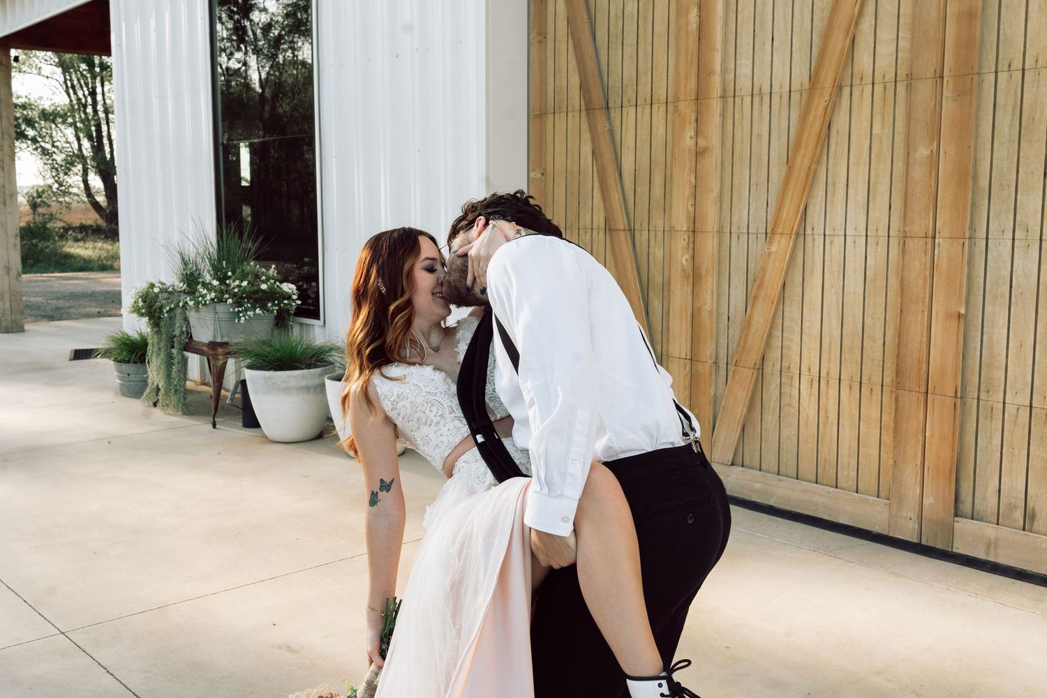 A romantic dance scene unfolds in front of a white barn with wooden doors.