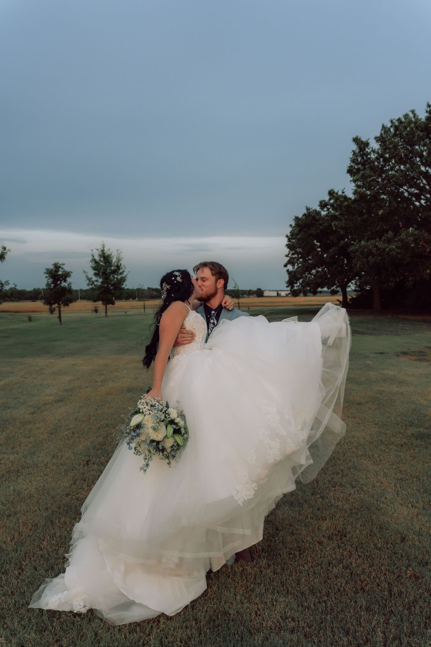 Elegant bridal portraits showcase flowing white gown in natural outdoor setting.