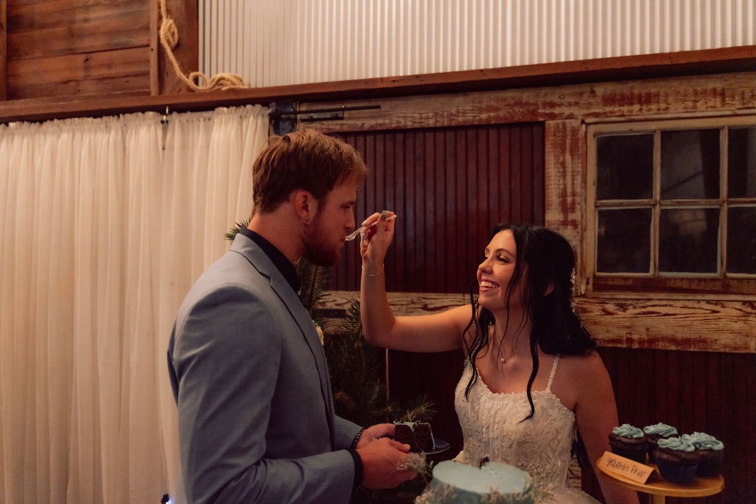 A tender moment between newlyweds during their wedding reception in a rustic barn setting.