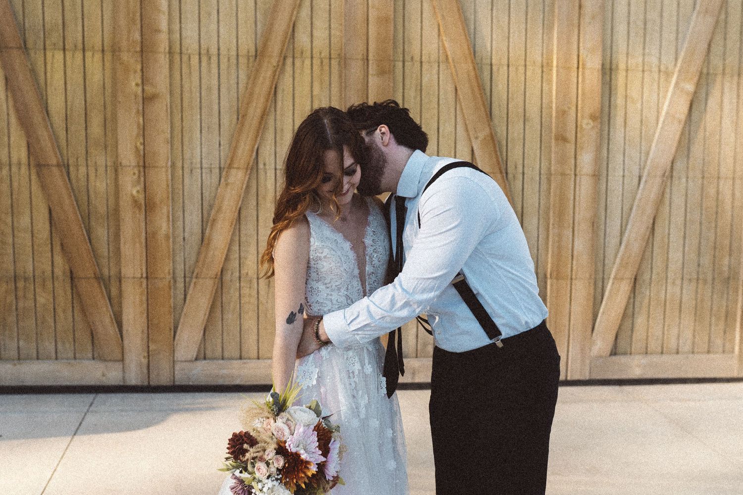 Bride and groom in romantic poses against wooden barn interior.