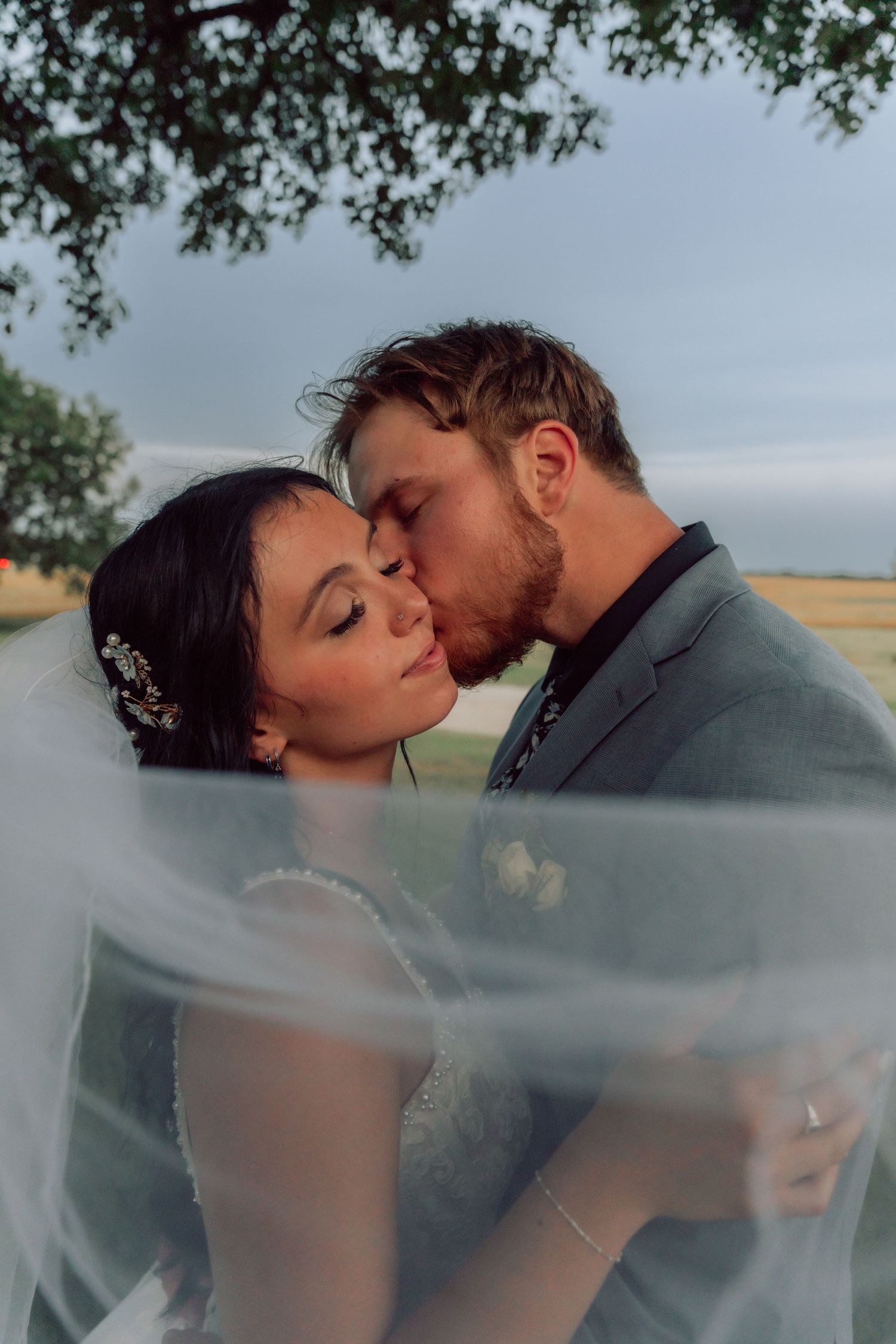 A romantic wedding portrait with the couple embracing under a flowing veil.