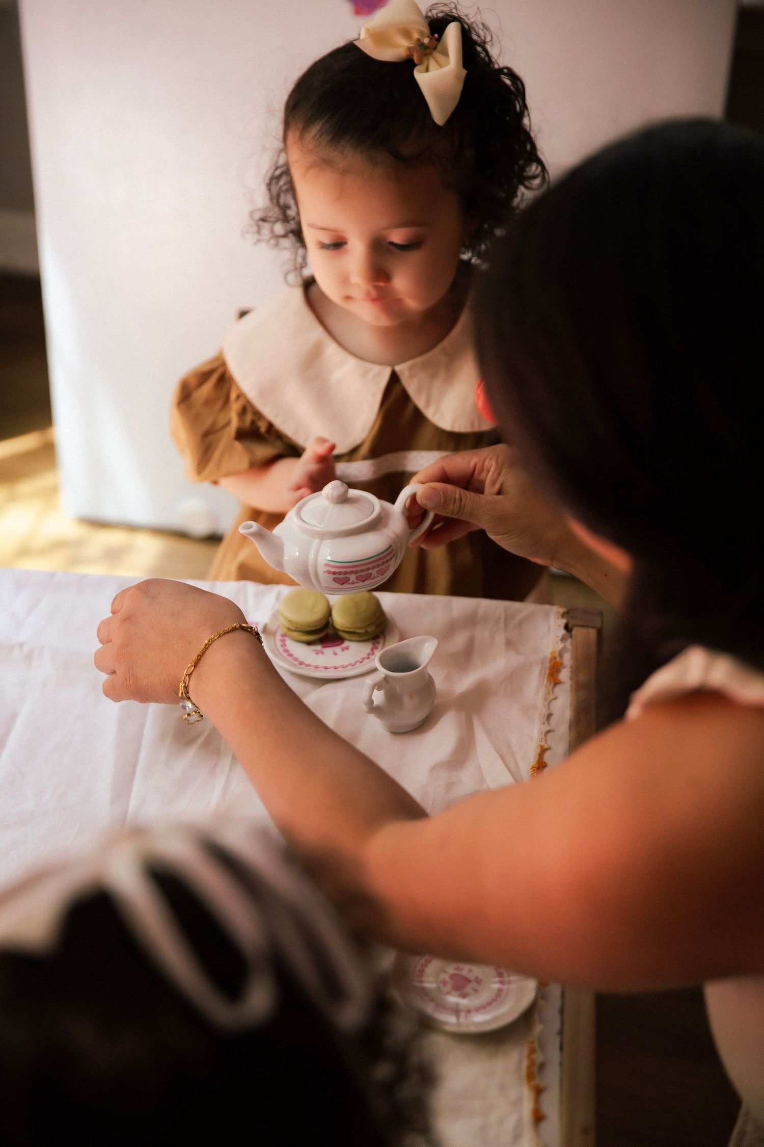 Mom helping toddler girl at a tea party