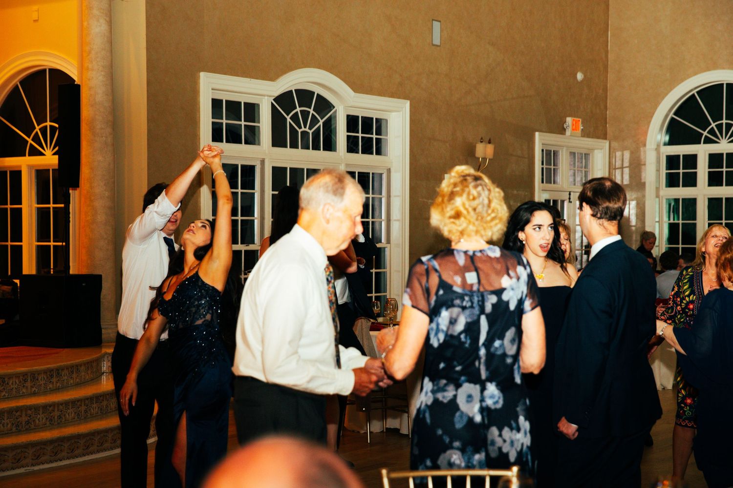 Wedding guests dancing and socializing on outdoor patio at evening reception.