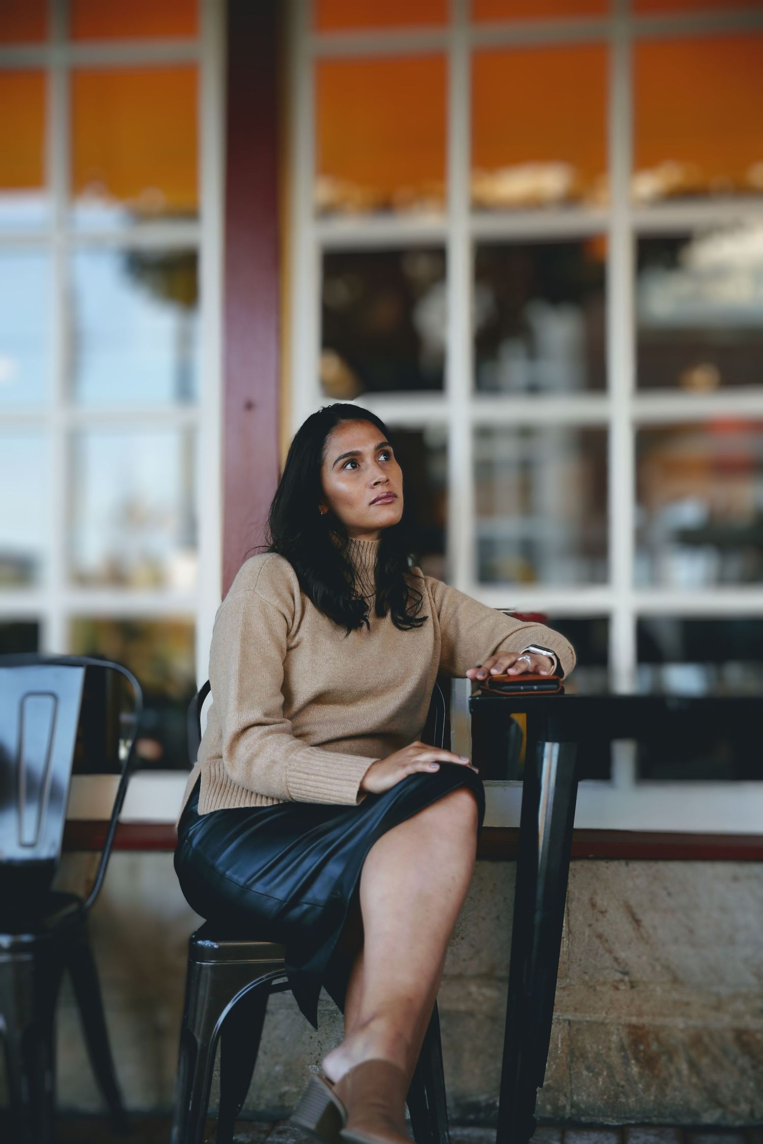 Female model with crossed legs sitting outside a cafe