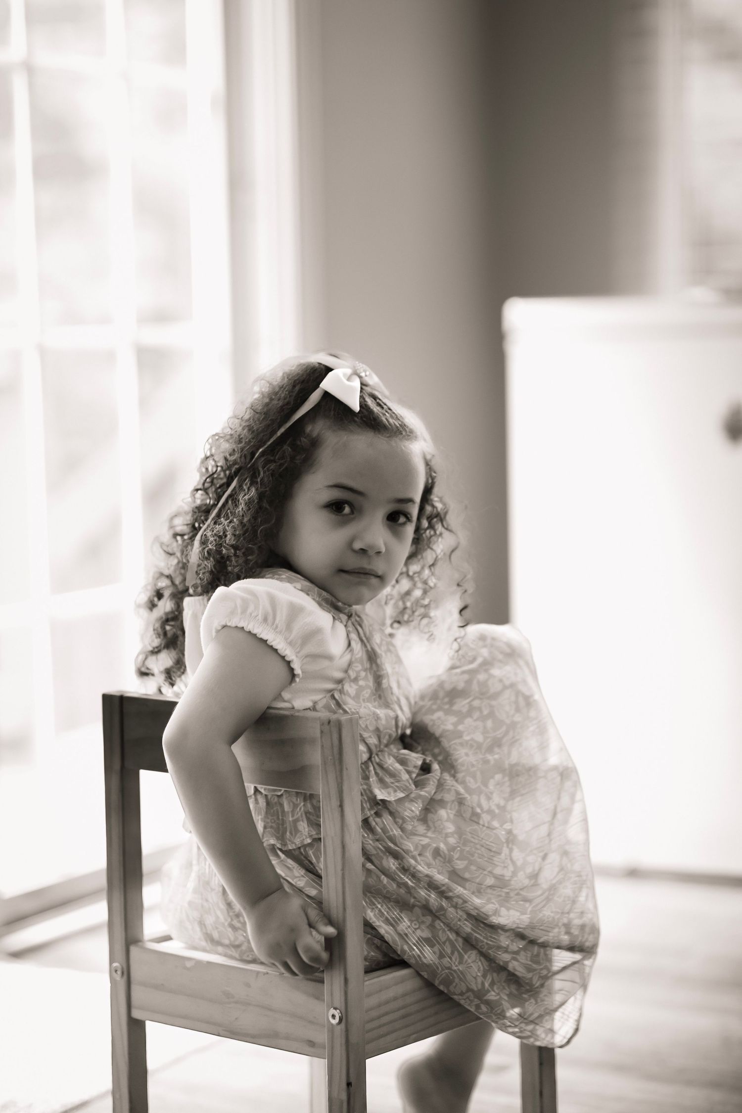 little girl with relaxed pose in wooden chair