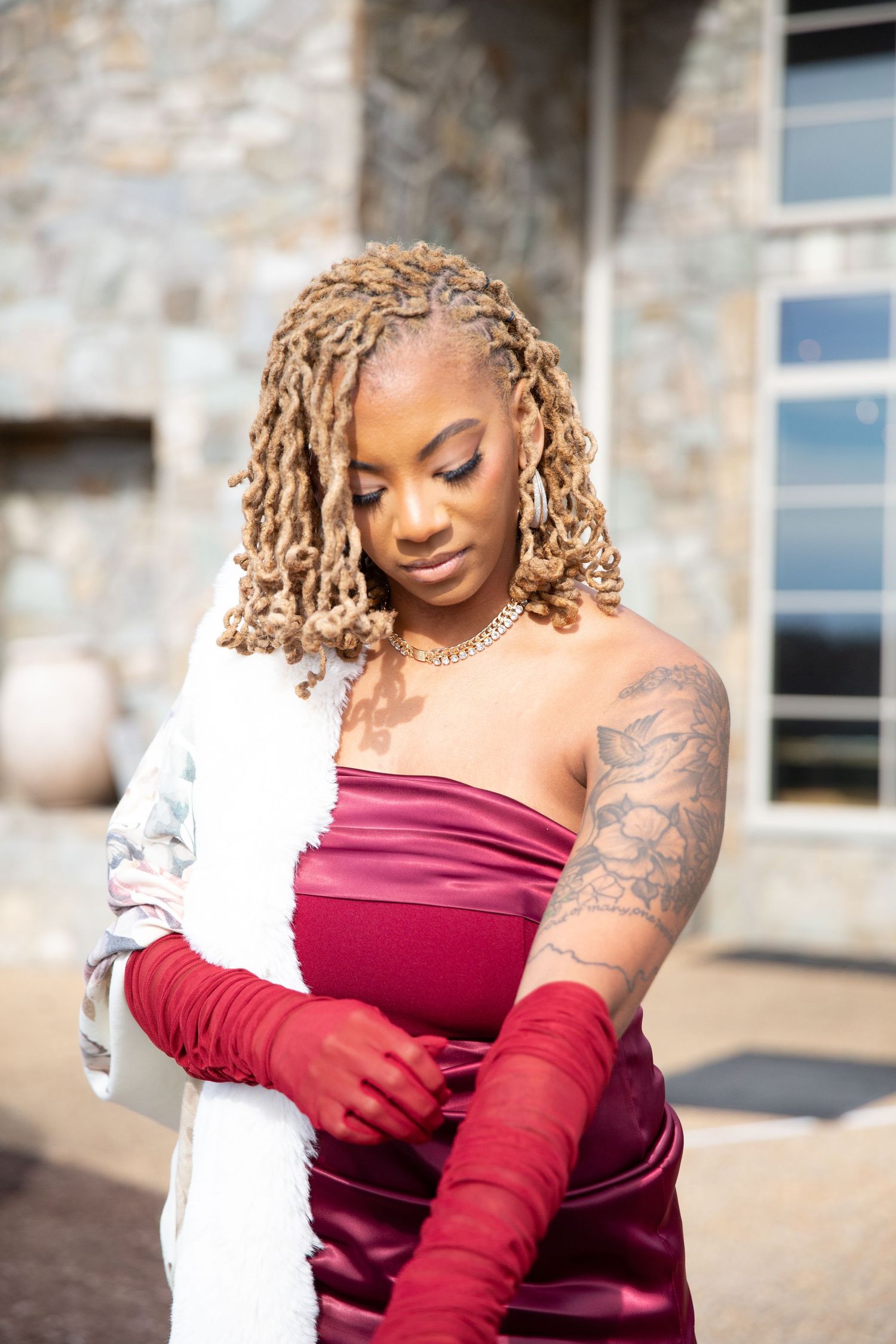 Black woman in red strapless gown and long red gloves posing.